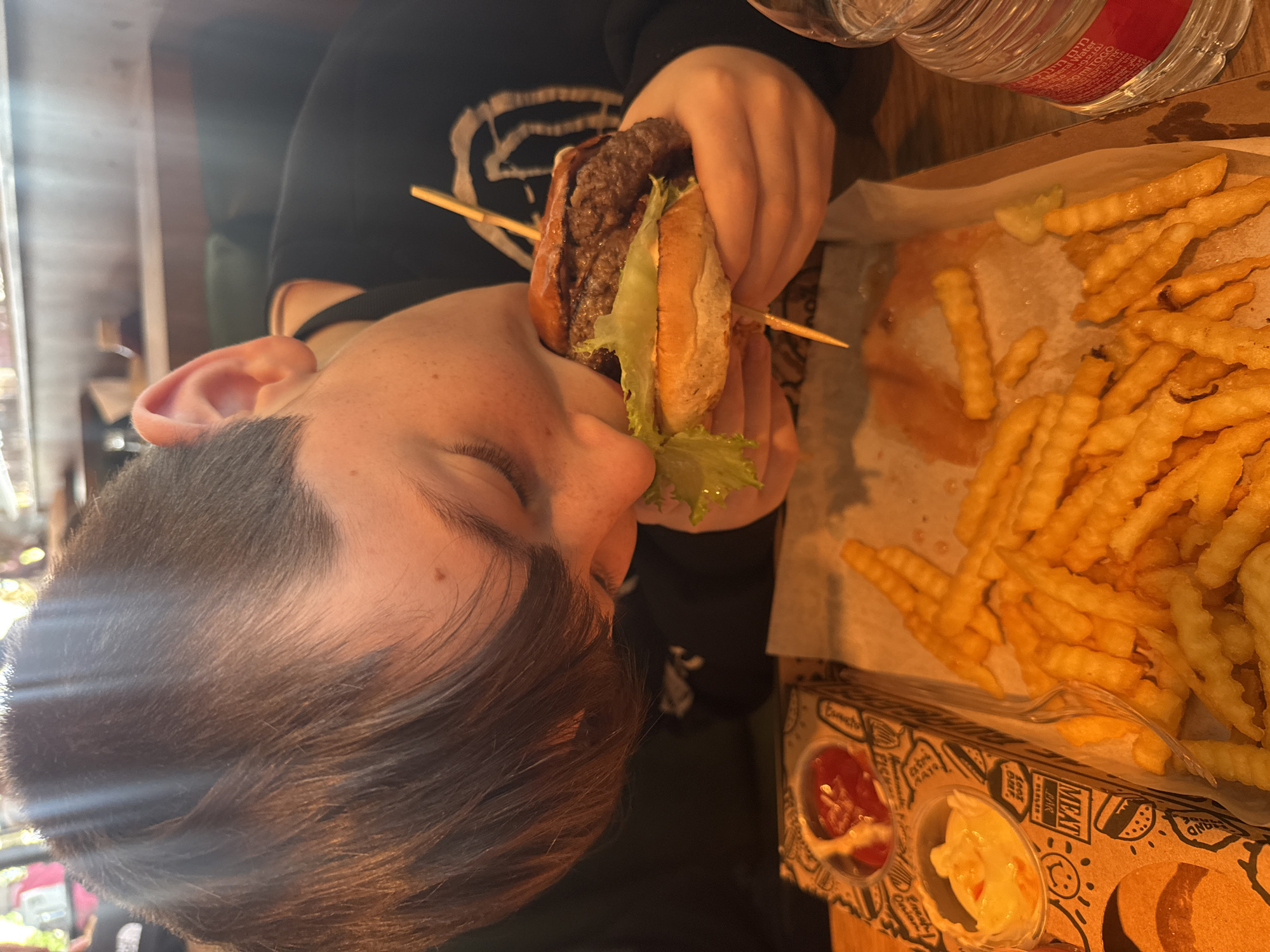 Young person enjoys burger and fries in Ramat HaSharon