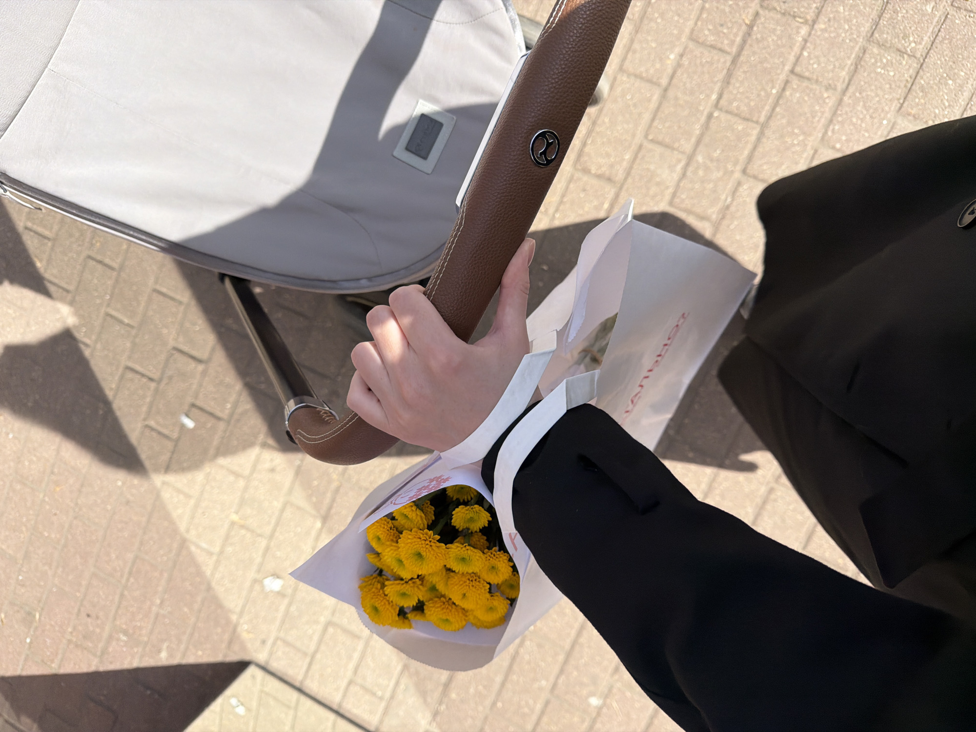 Parent with stroller carries yellow flowers in Khimki