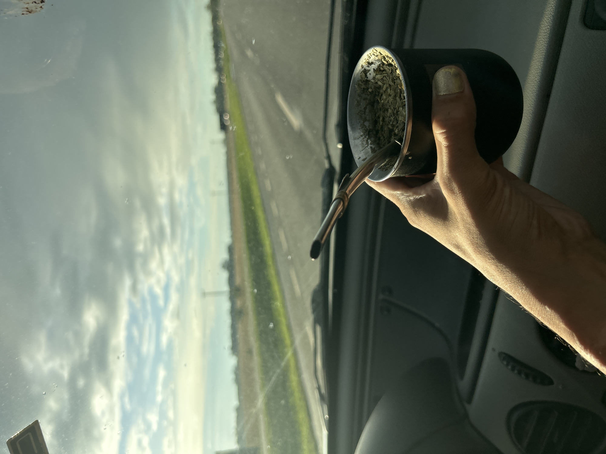 Traveler drinks traditional mate while driving through Argentine countryside