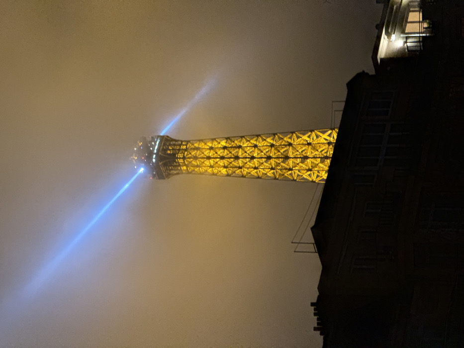 Eiffel Tower glows yellow through thick fog, Paris evening