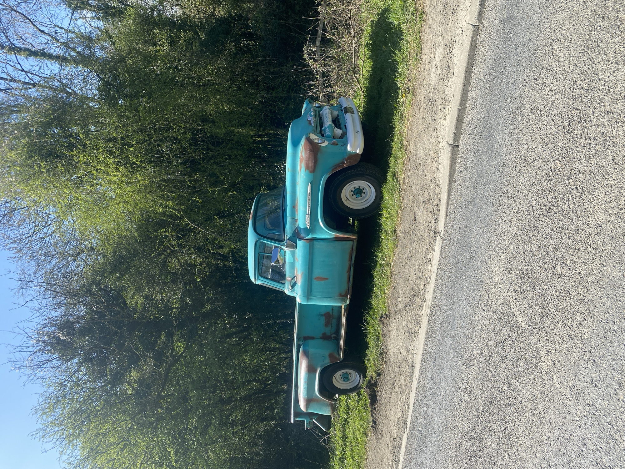 Rusted turquoise pickup truck parked roadside in Nantmawr