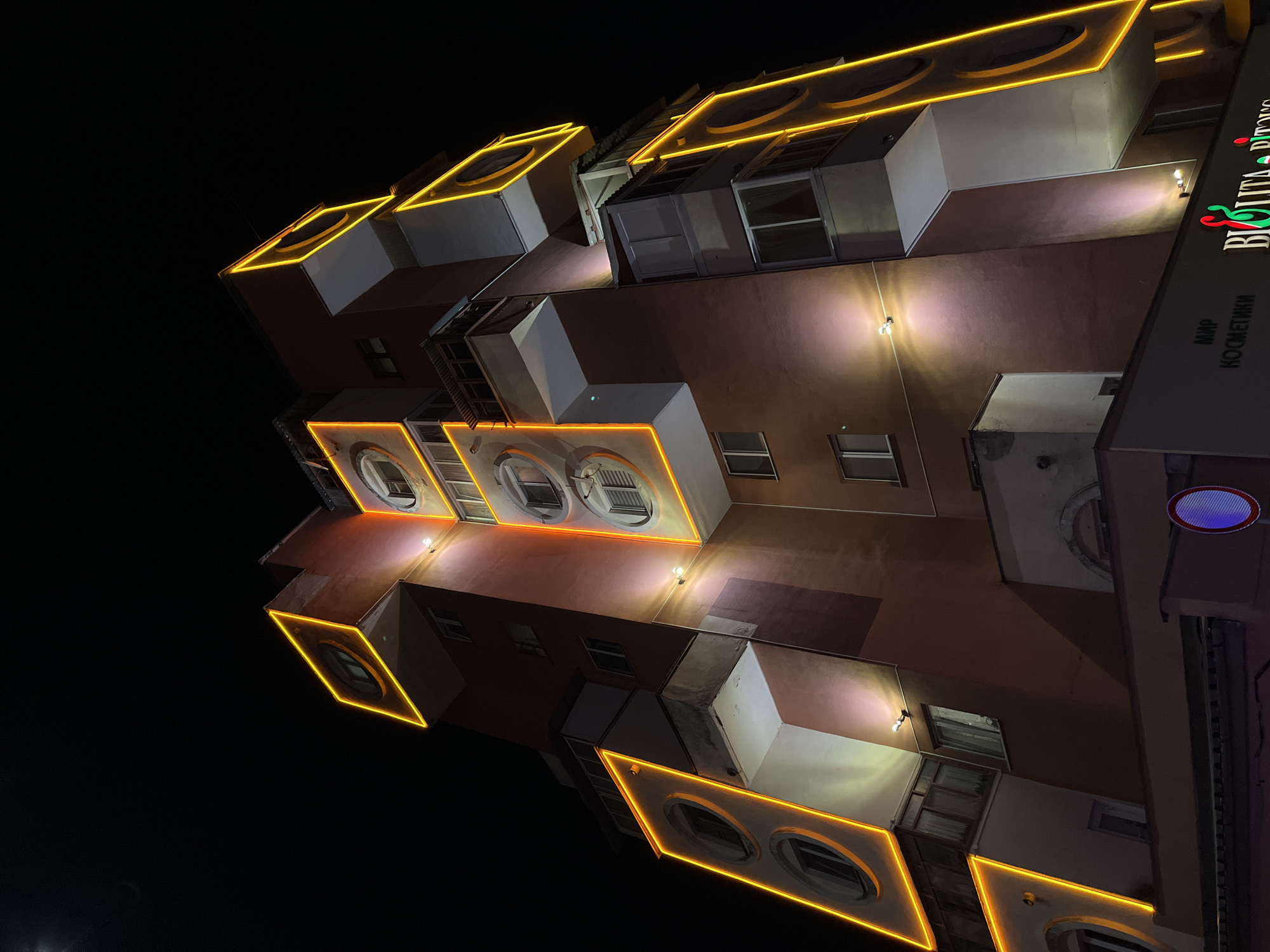 Brutalist apartment block lit up in yellow neon, Babruysk night