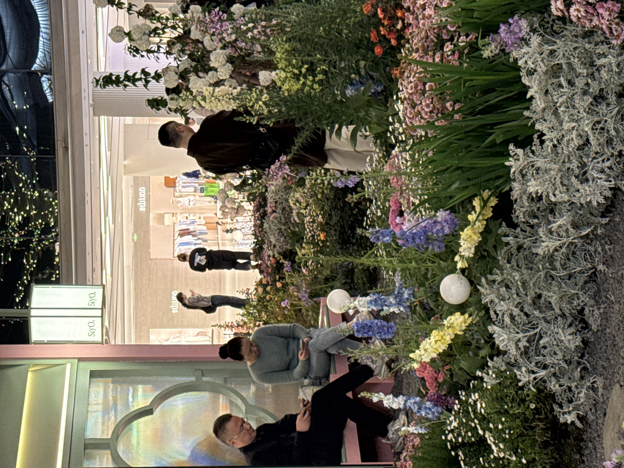 Evening shoppers stroll illuminated floral displays at Liangjiang mall