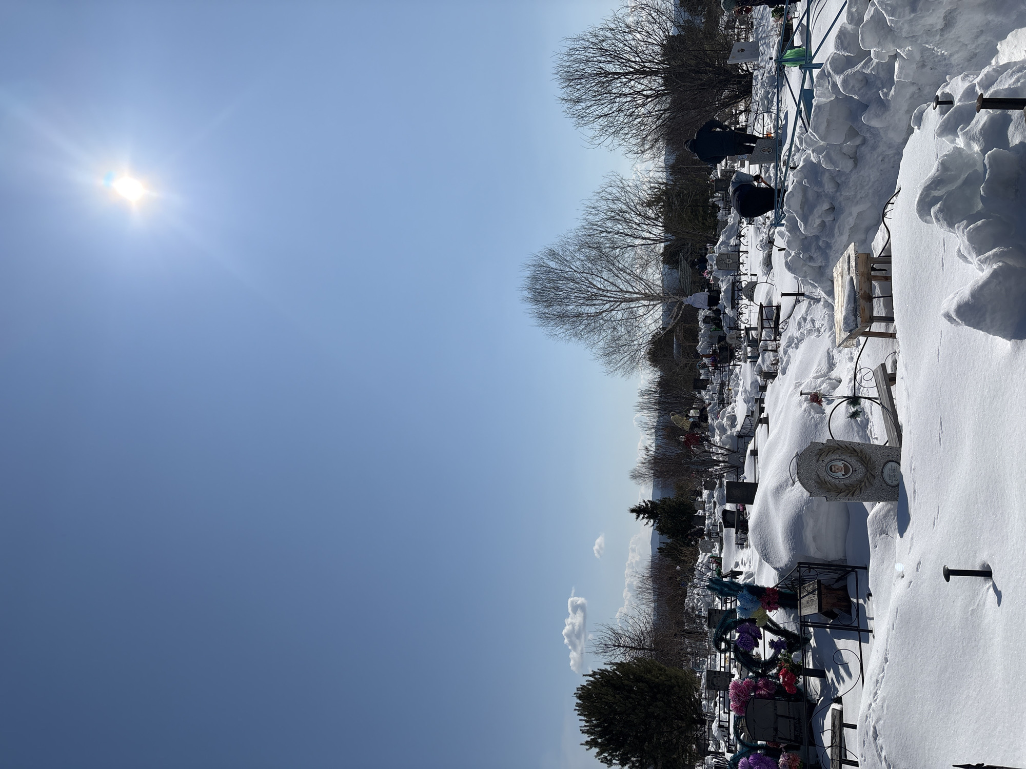Snow blankets cemetery in Невон, Russia under clear skies