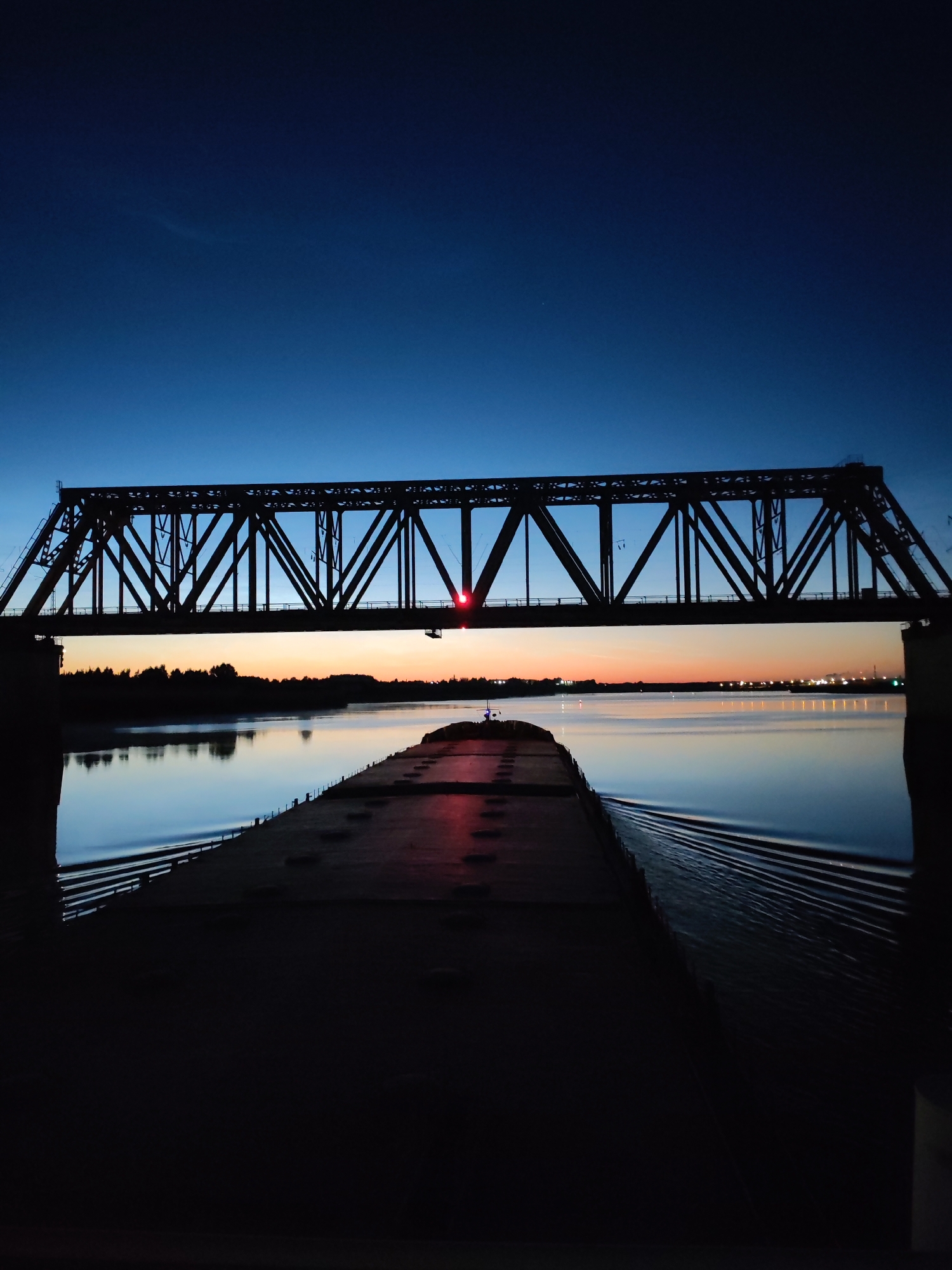 Barges and bridges along a waterway at dusk