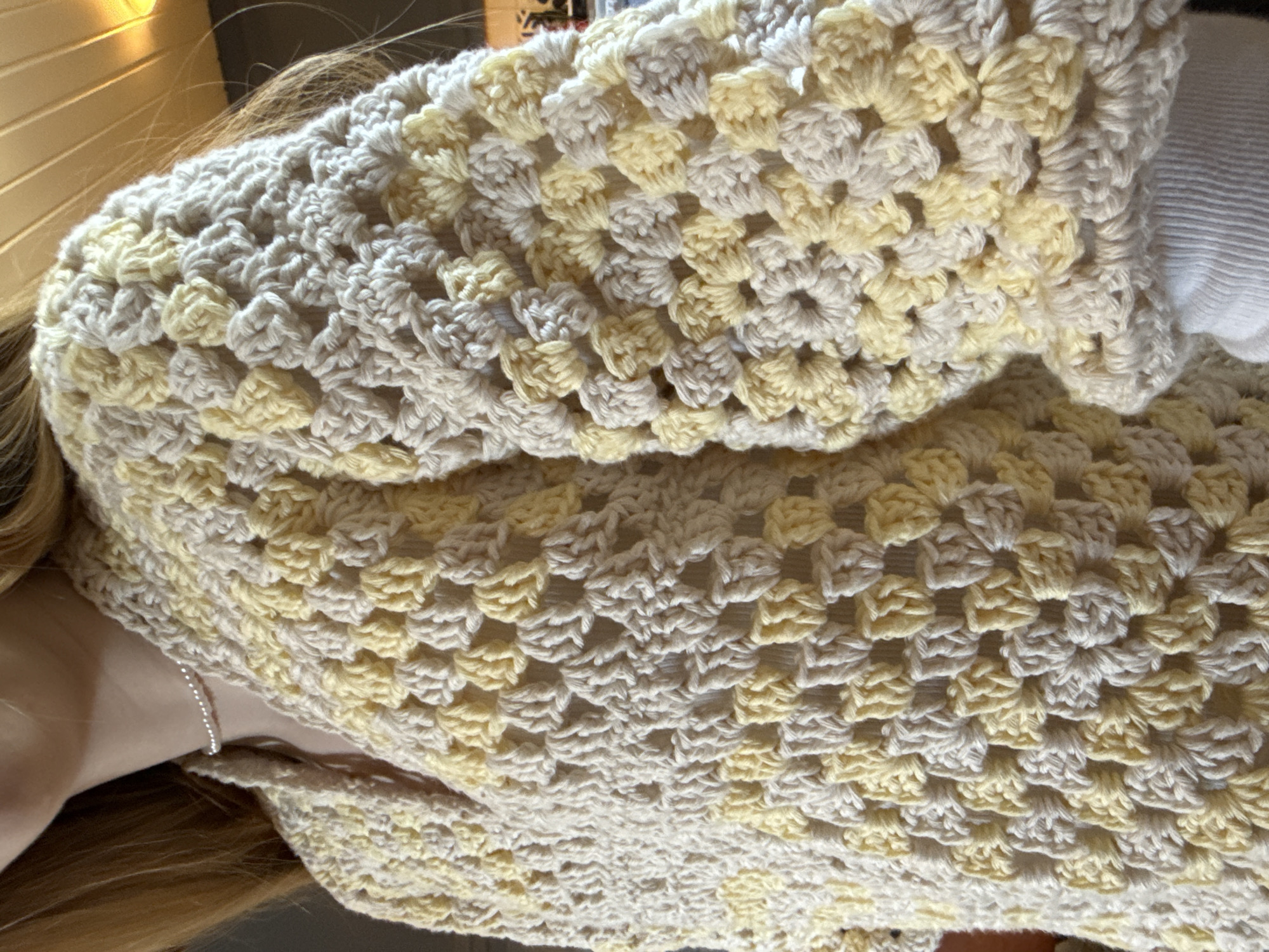 Woman showcases crocheted yellow sweater in Swedish kitchen