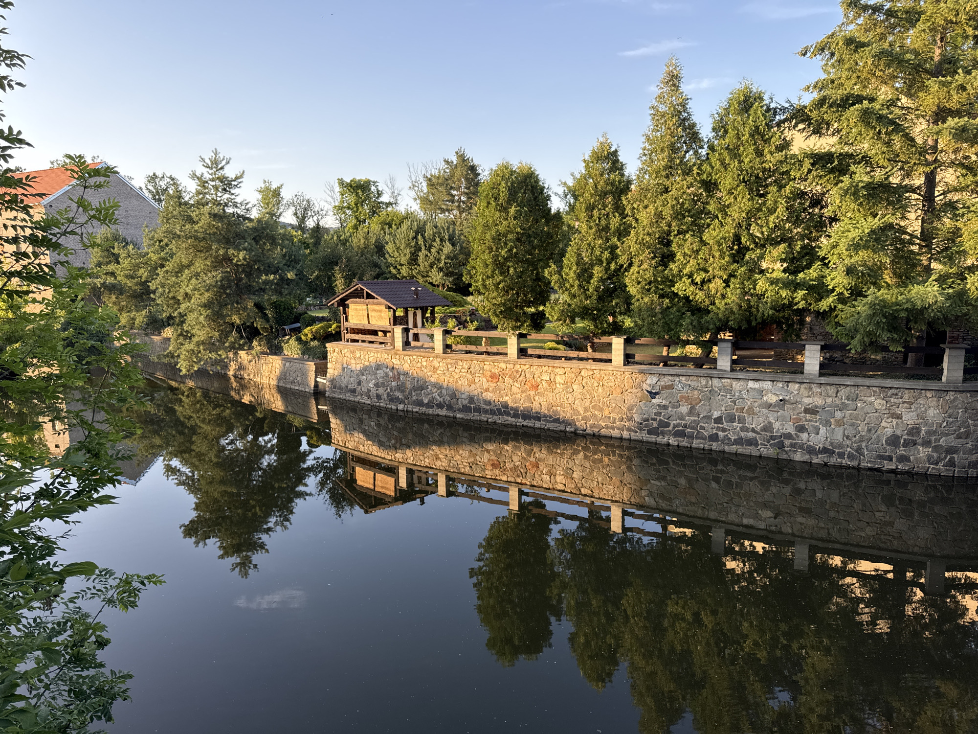 Still water and stone walls in golden afternoon light, Beroun