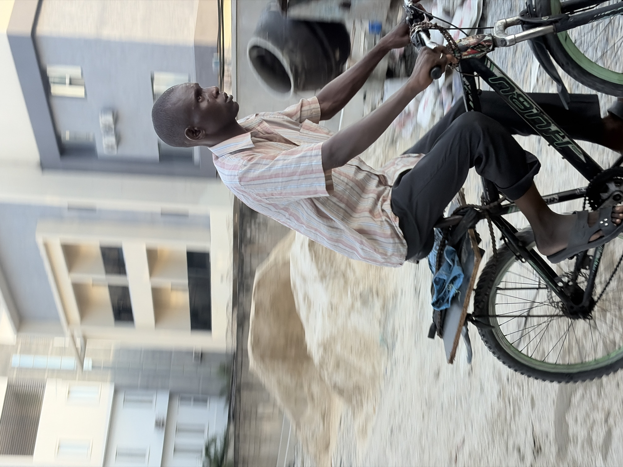 Cyclist spotted on dusty road near modern building in Moba