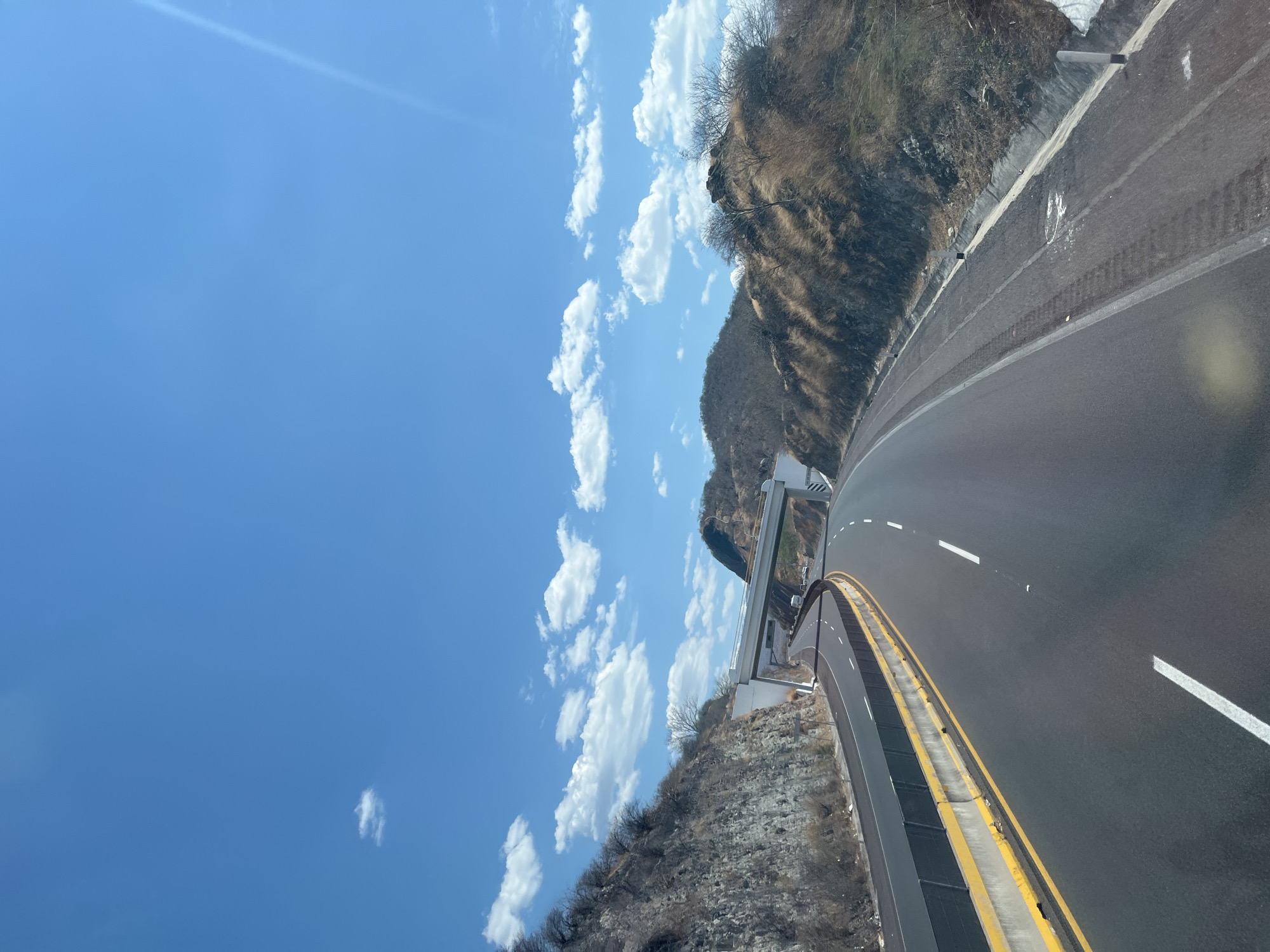 Highway curves through hilly Mexican terrain under blue skies