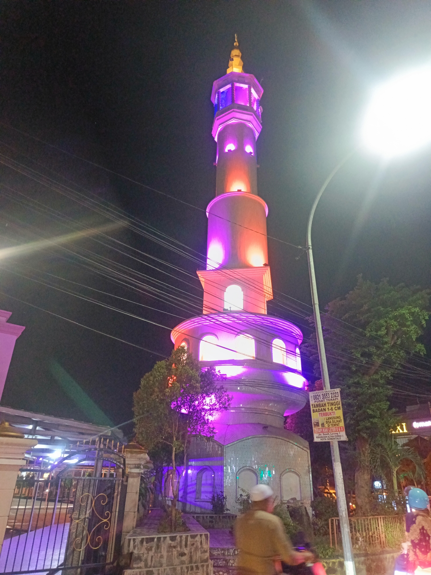 Gorontalo at night: lit minaret and neon-lined streets