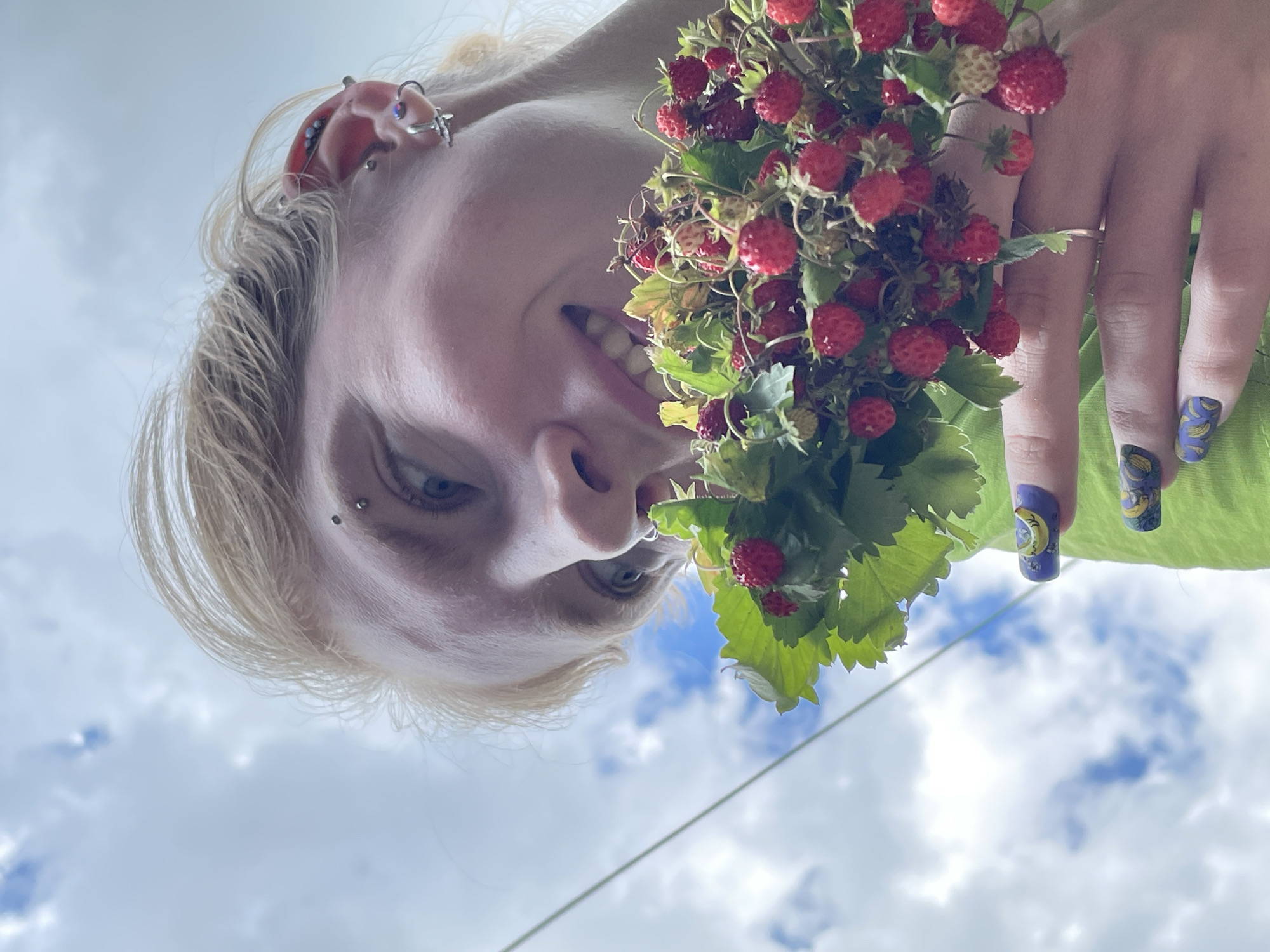 Wild strawberries held up to a cloudy Russian summer sky