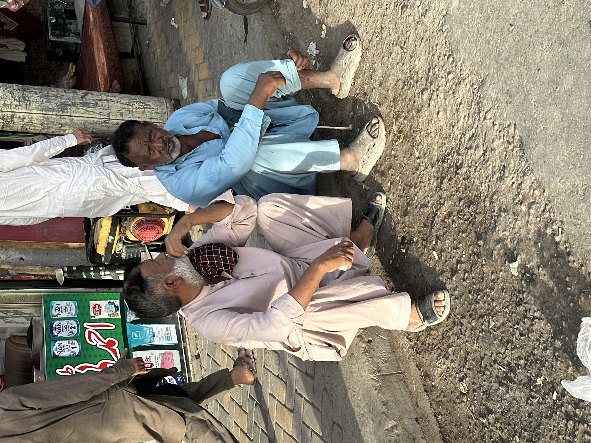 Street market activity in Quetta — shops, phones, and live poultry
