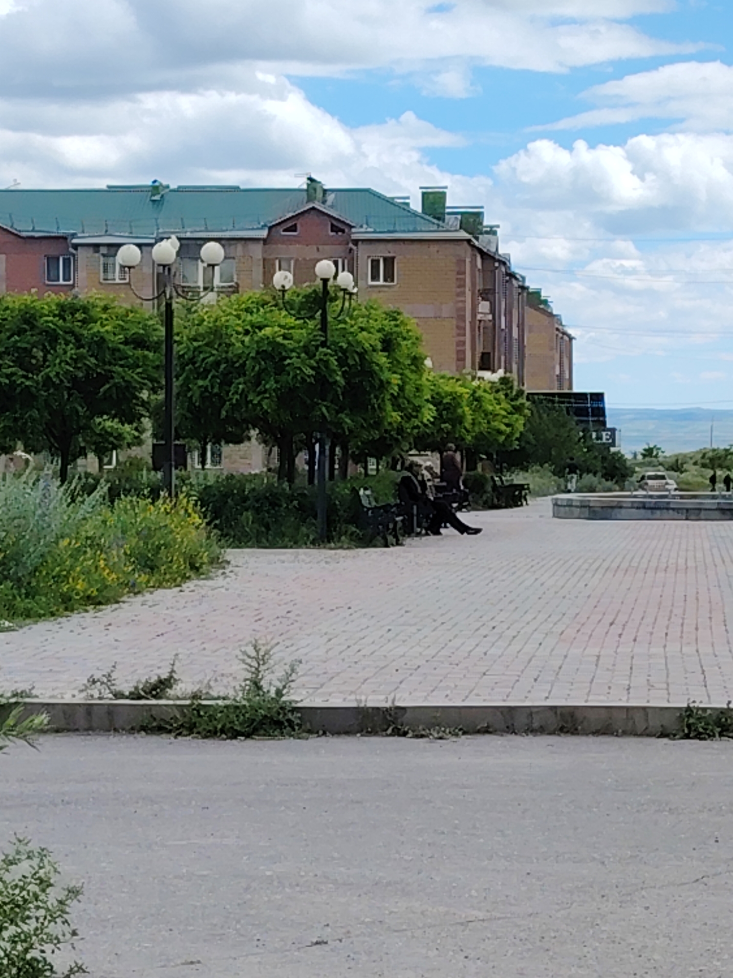 Brick paths, wildflowers, and a stone monument in an urban park