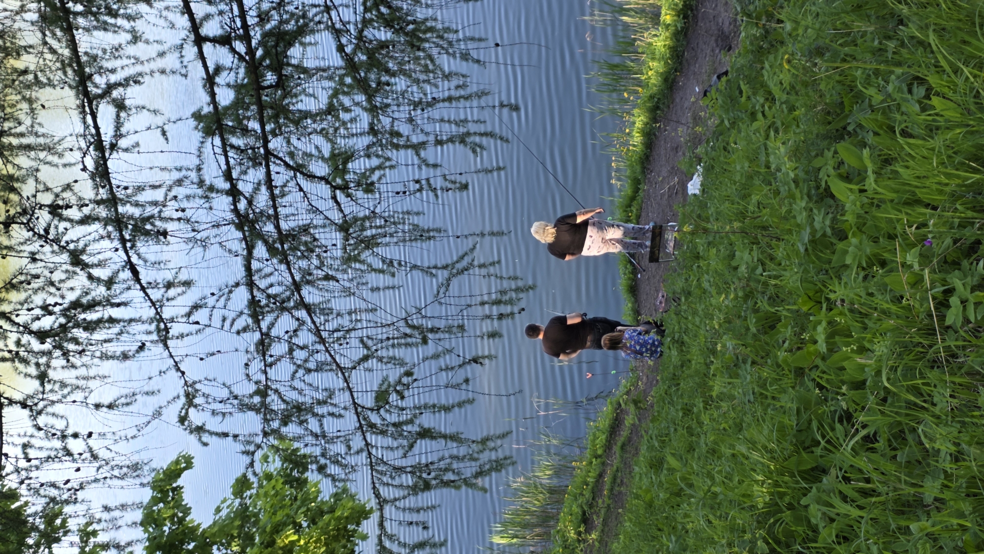 Two people fish along tranquil waterway in Gatchina, Russia