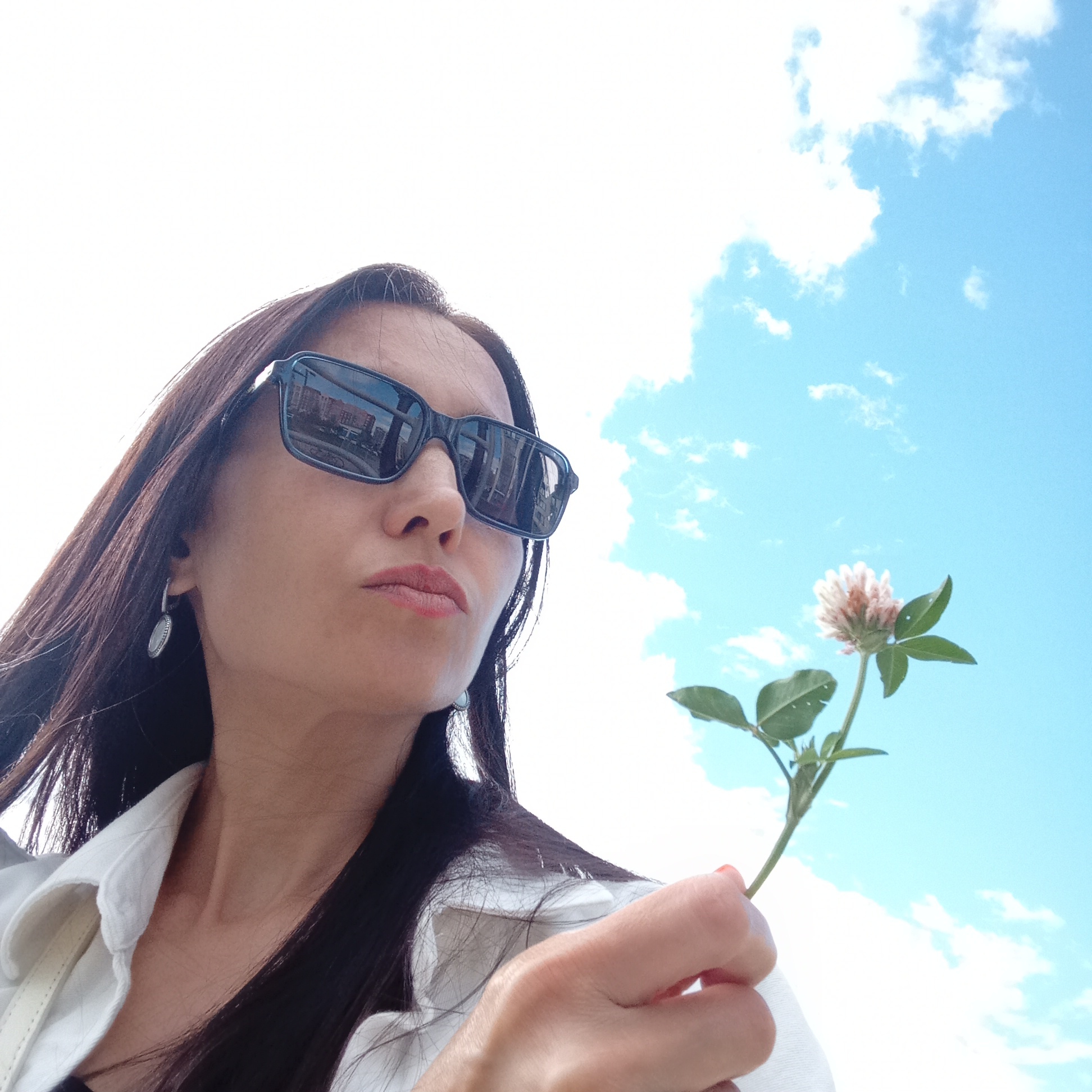 Woman photographs clover flower amid apartment buildings in Izhevsk