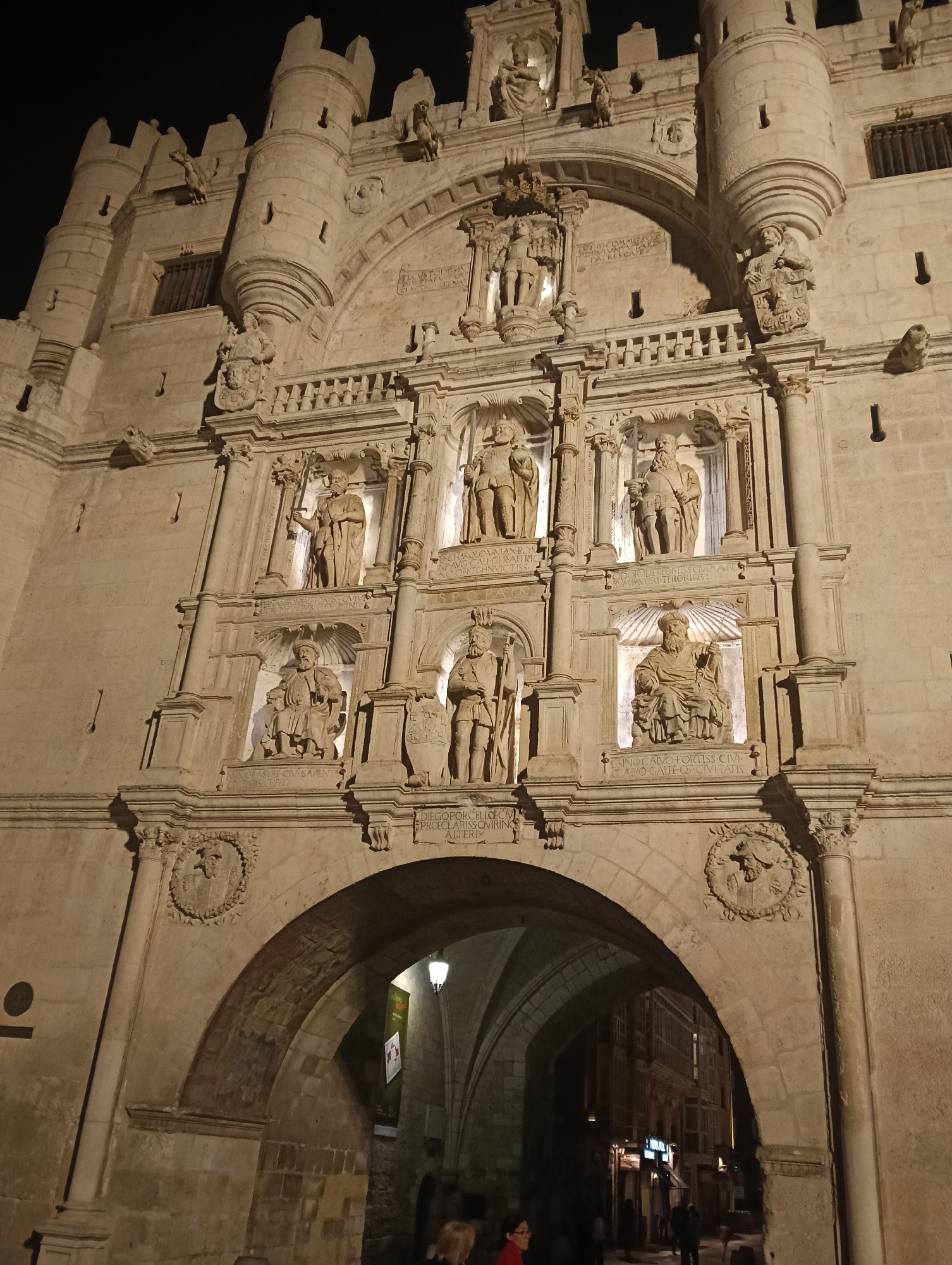 Uniformed marching band crosses street during nighttime procession in Burgos