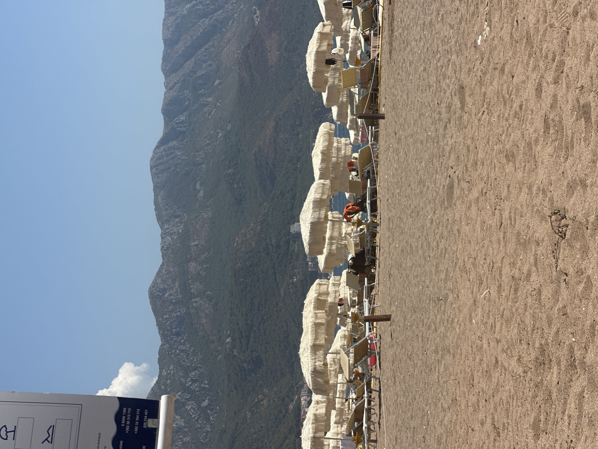 Busy beach day in Boreti, Montenegro, with parasailing overhead