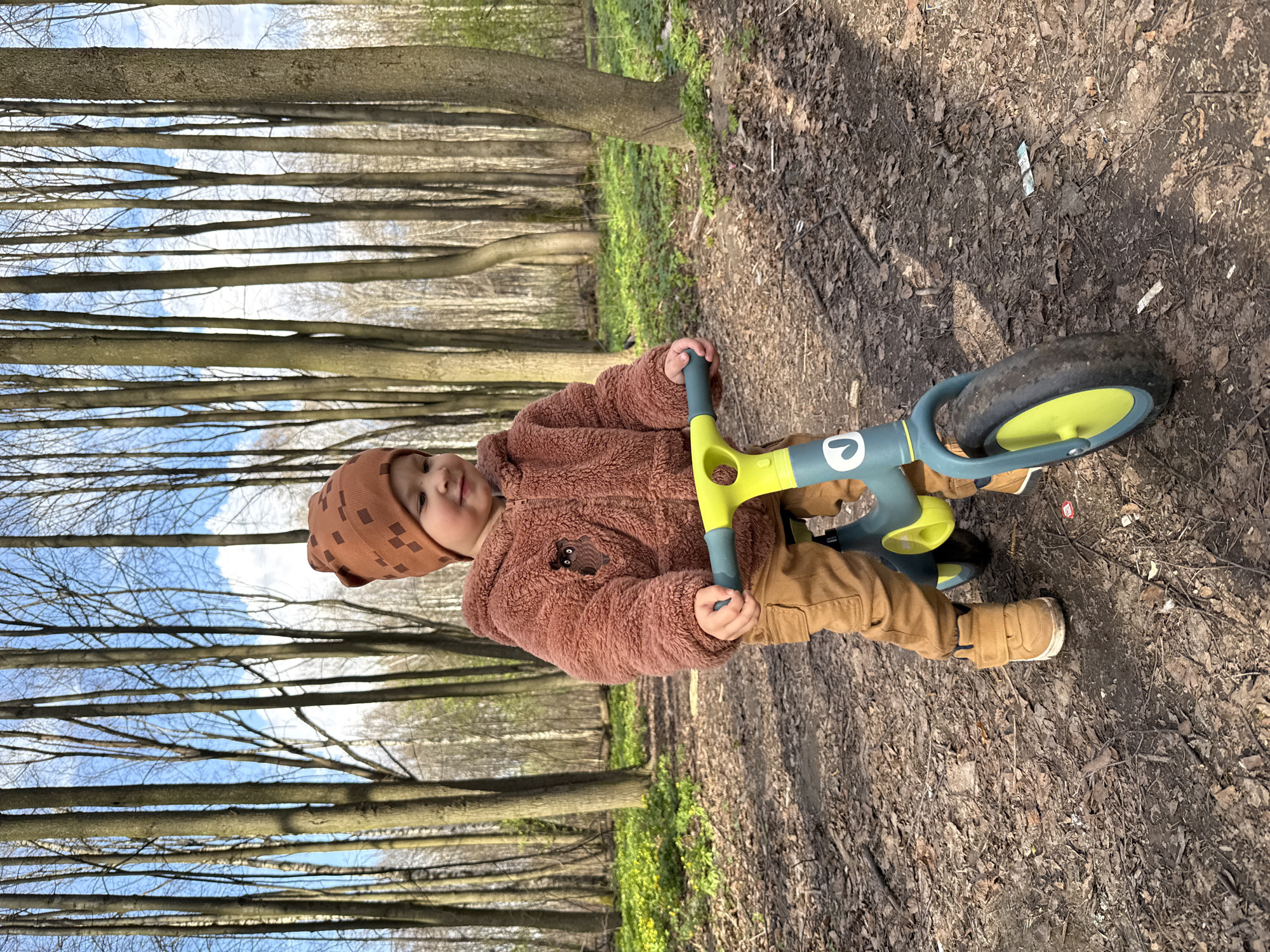 Child with balance bike spotted on wooded path in Rusanovo