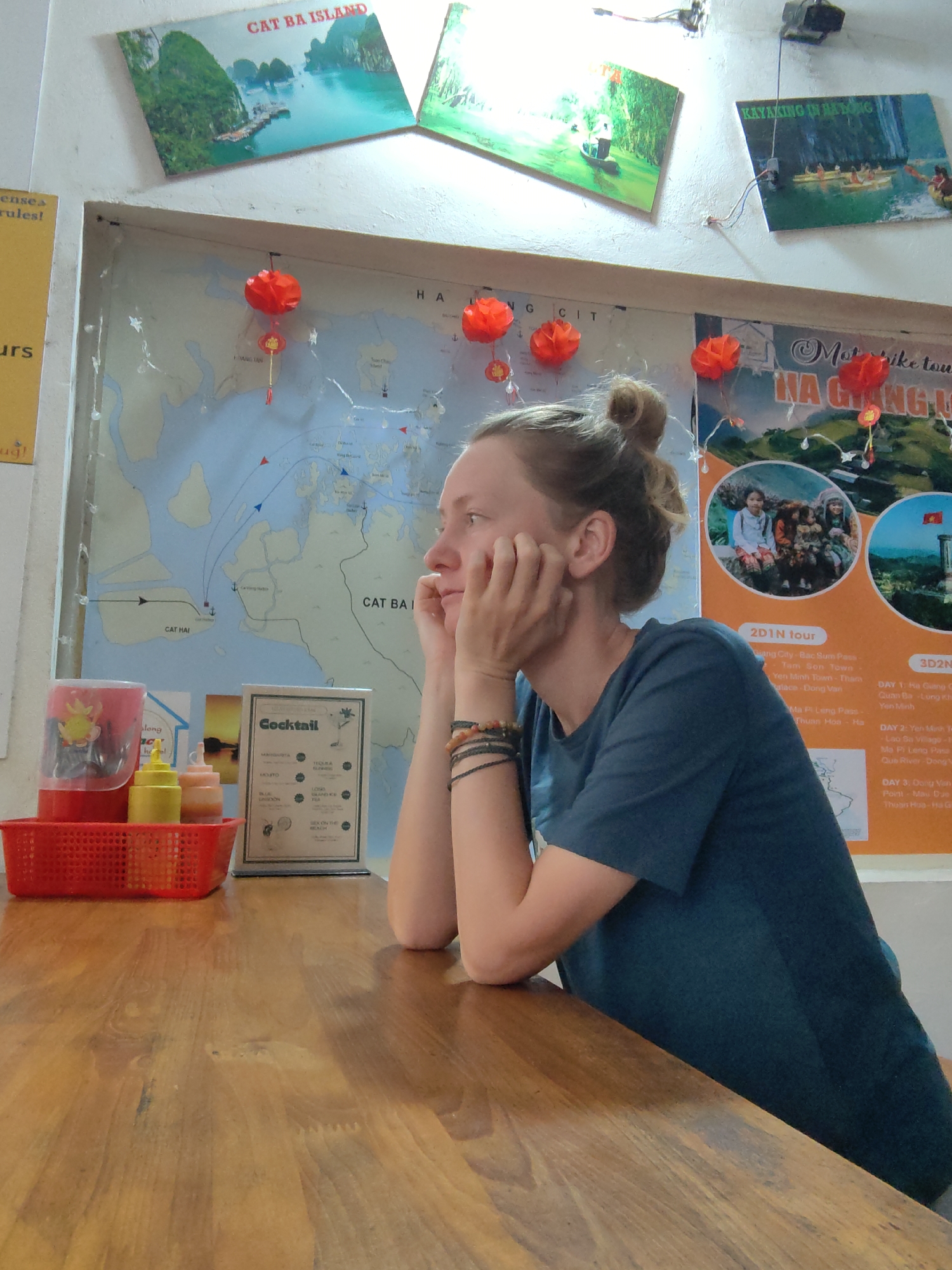Woman contemplates at table with Cat Ba Island memorabilia