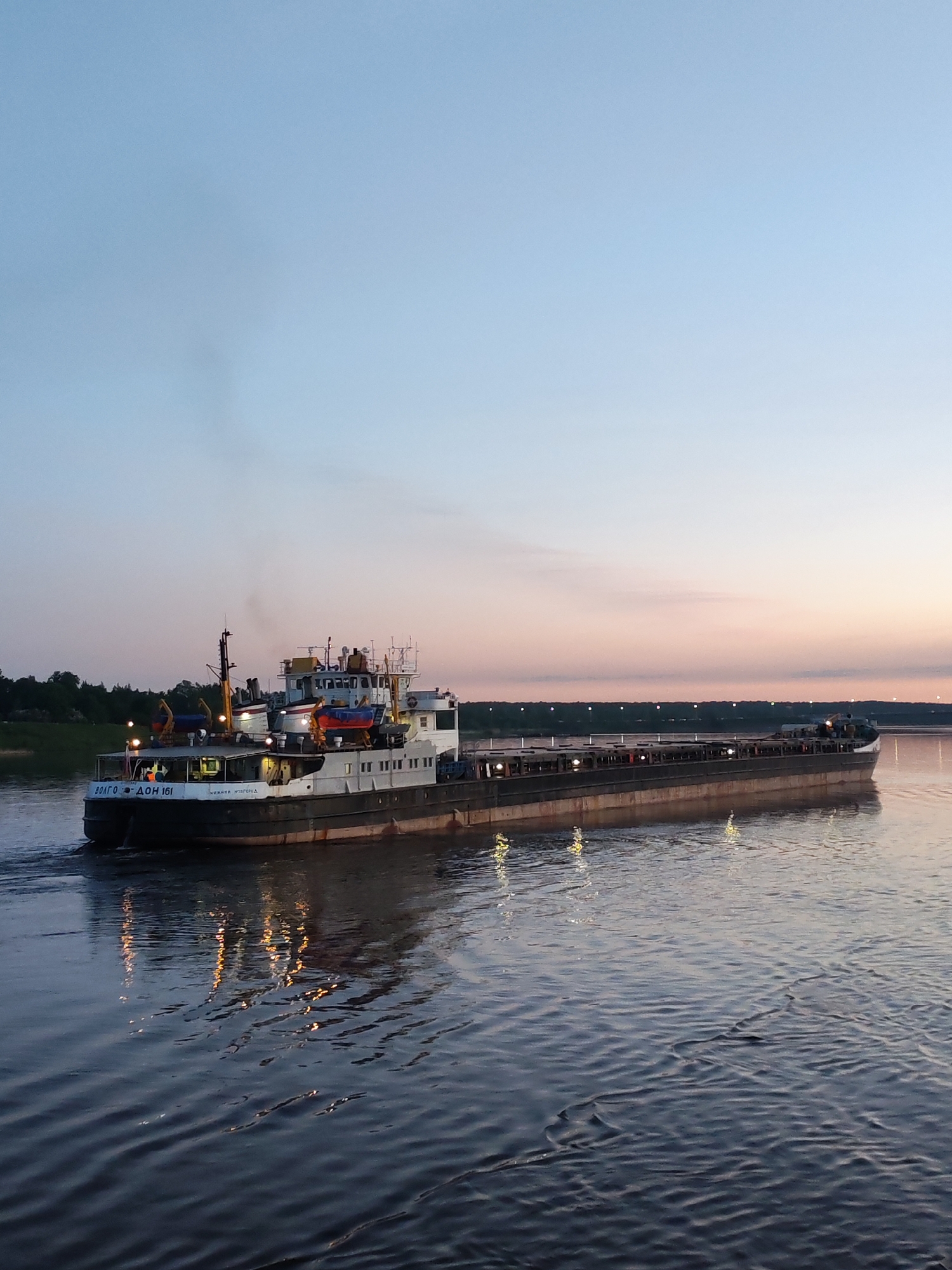 Evening river scenes show cargo barge and cable bridge
