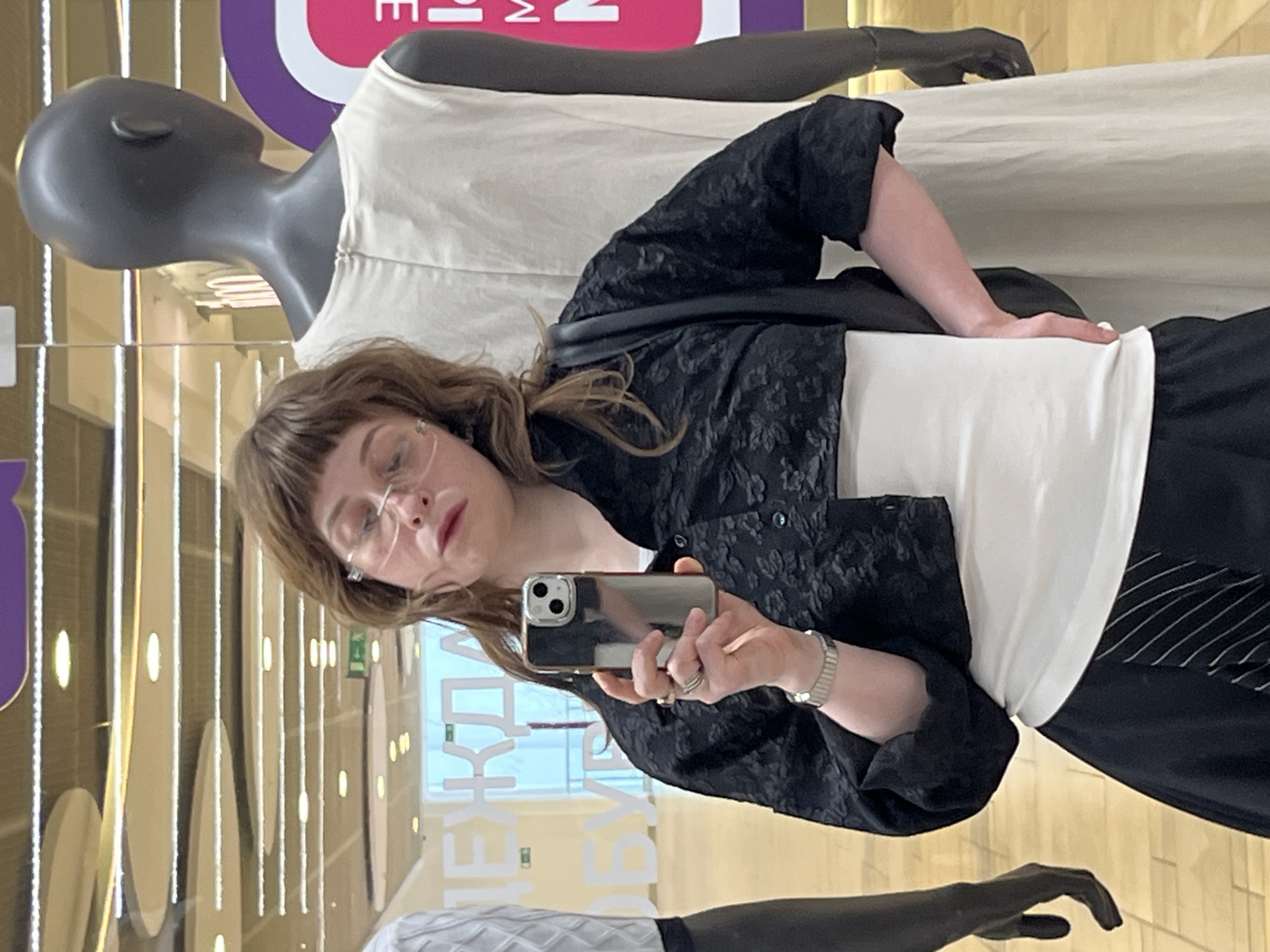 Mirror selfies in a Moscow clothing store, mid-outfit decision