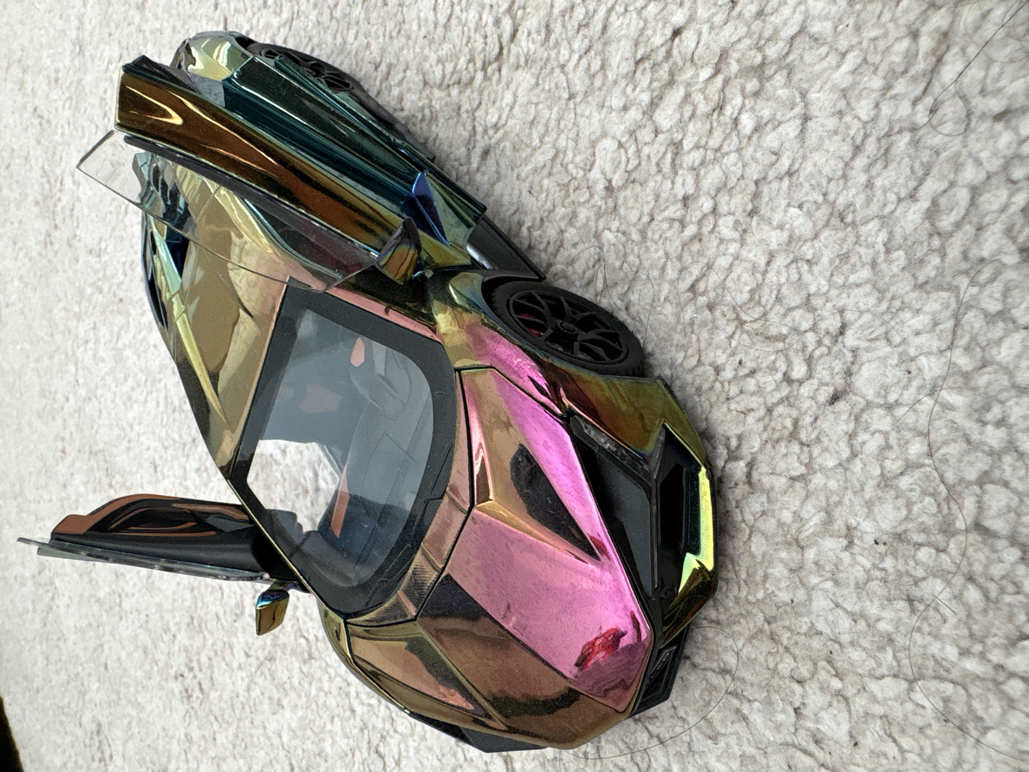 Multi-colored toy car with open door spotted on textured surface