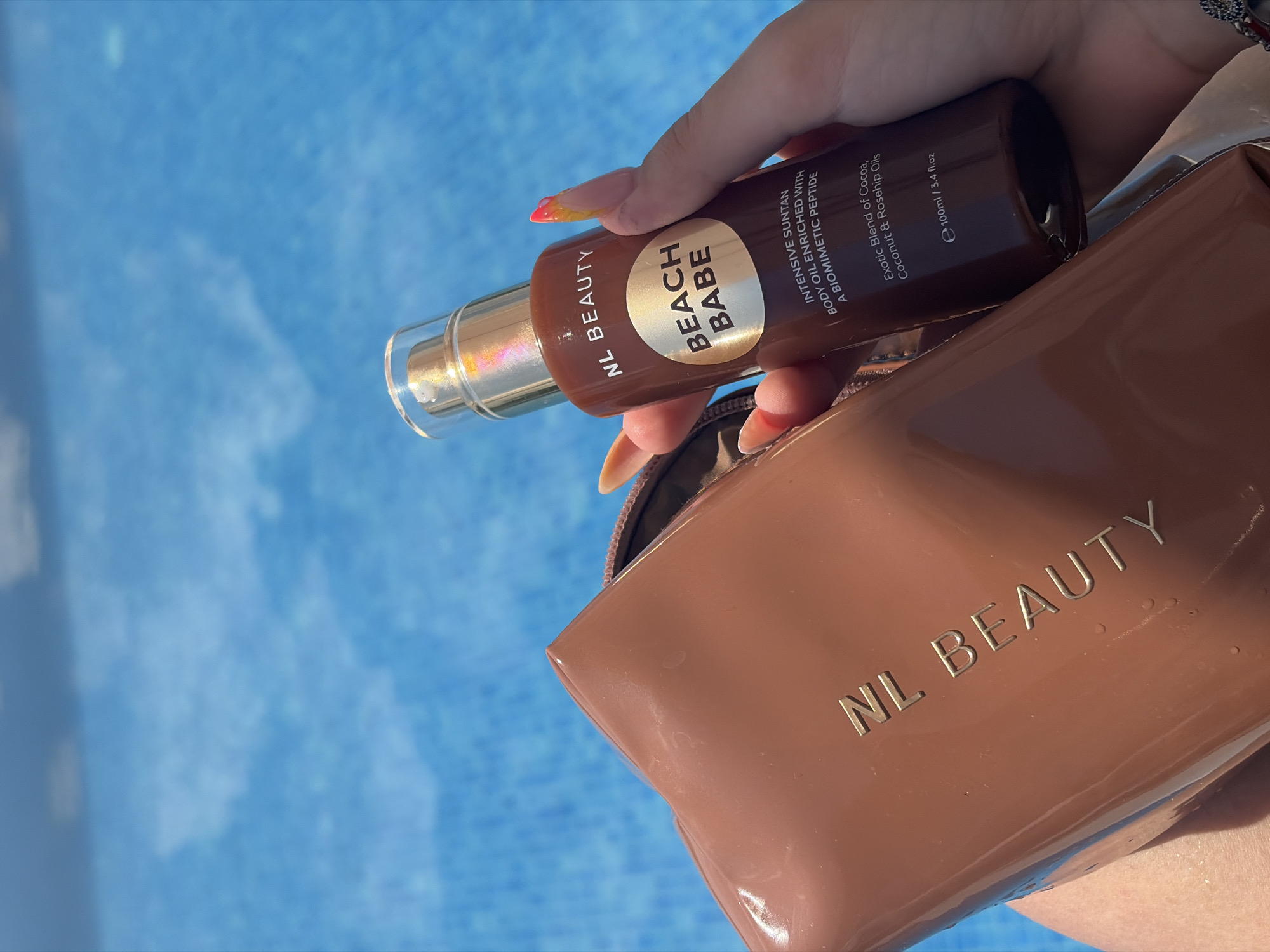 Sunny poolside moment with suntan oil and statement nails
