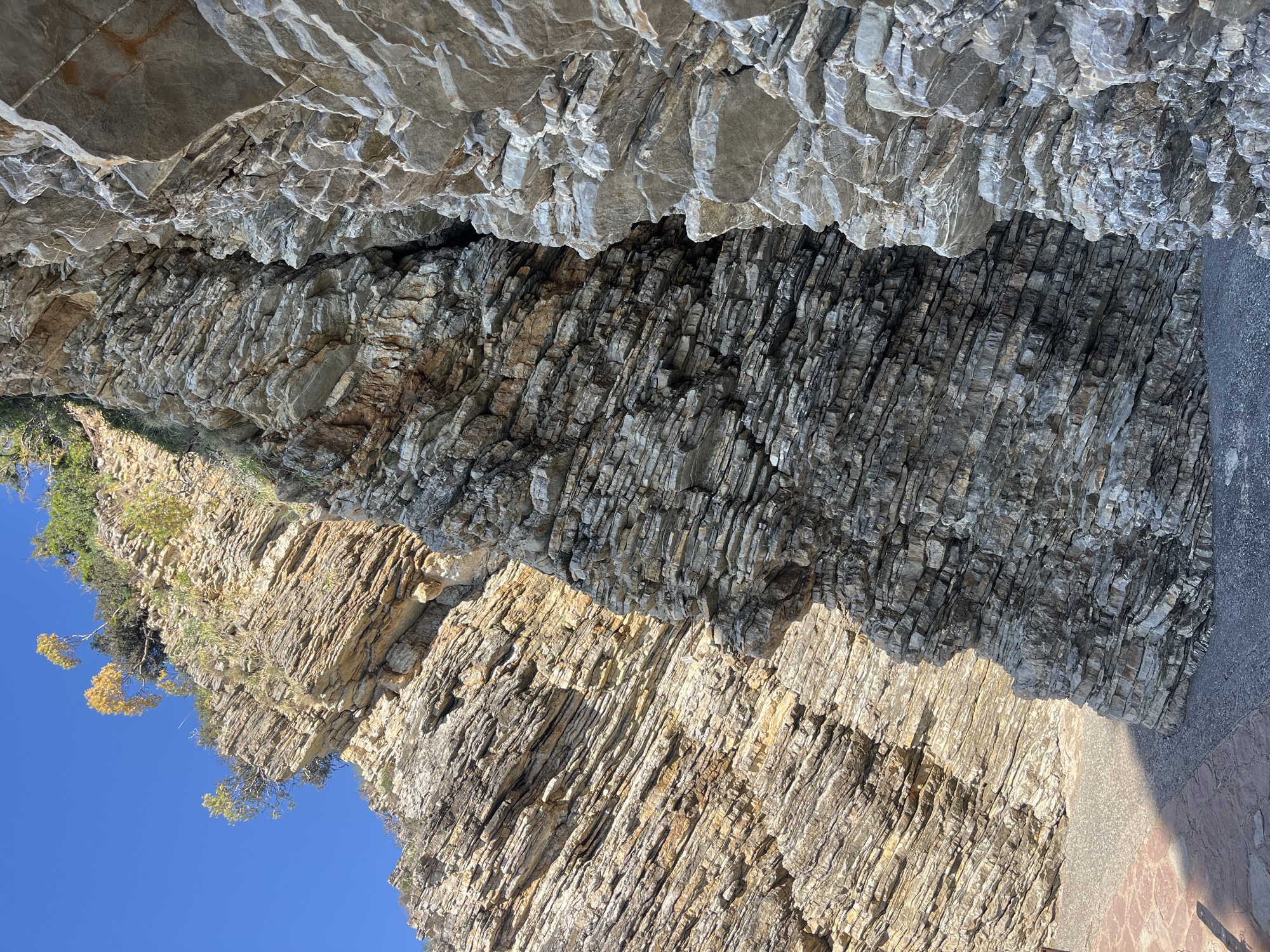 Person rests on stratified rock formation in Budva, Montenegro