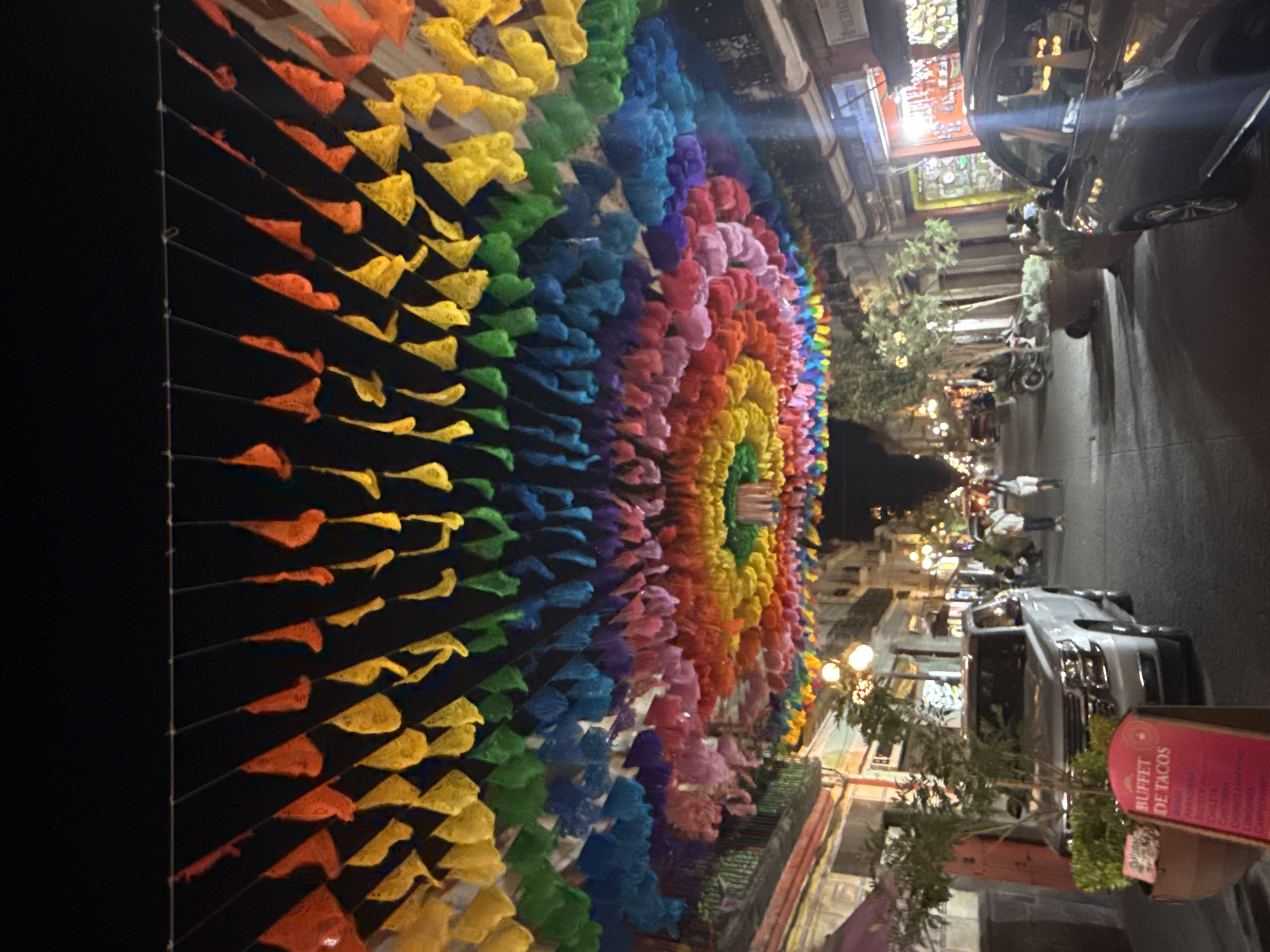 Colorful papel picado decorations illuminate Puebla street at night