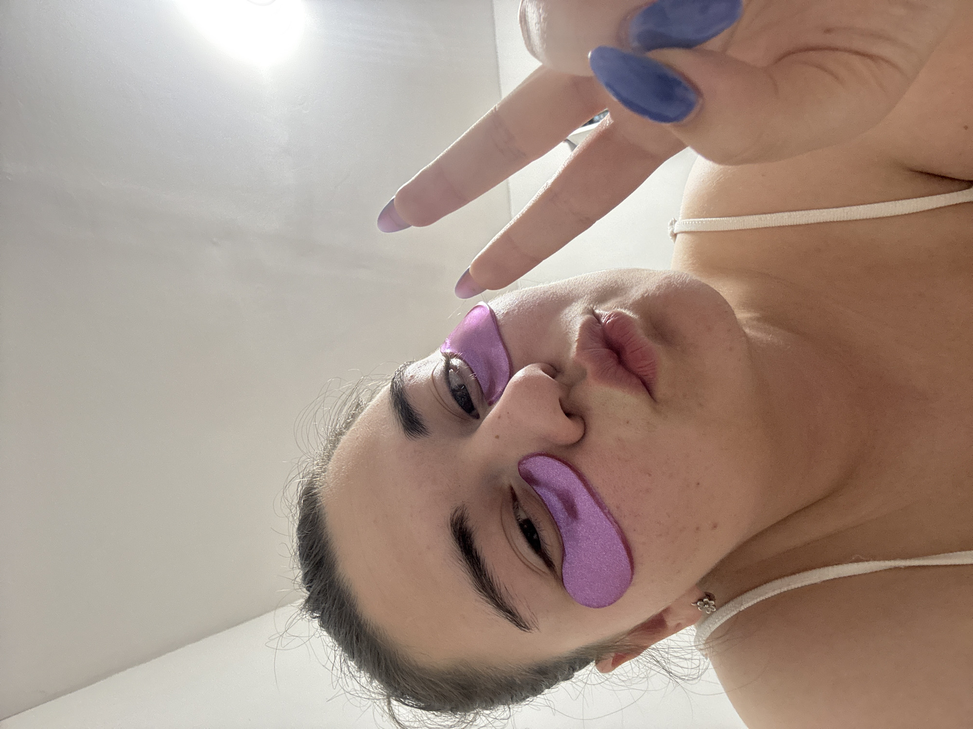 Woman applies purple under-eye patches in Zlatitsa beauty routine