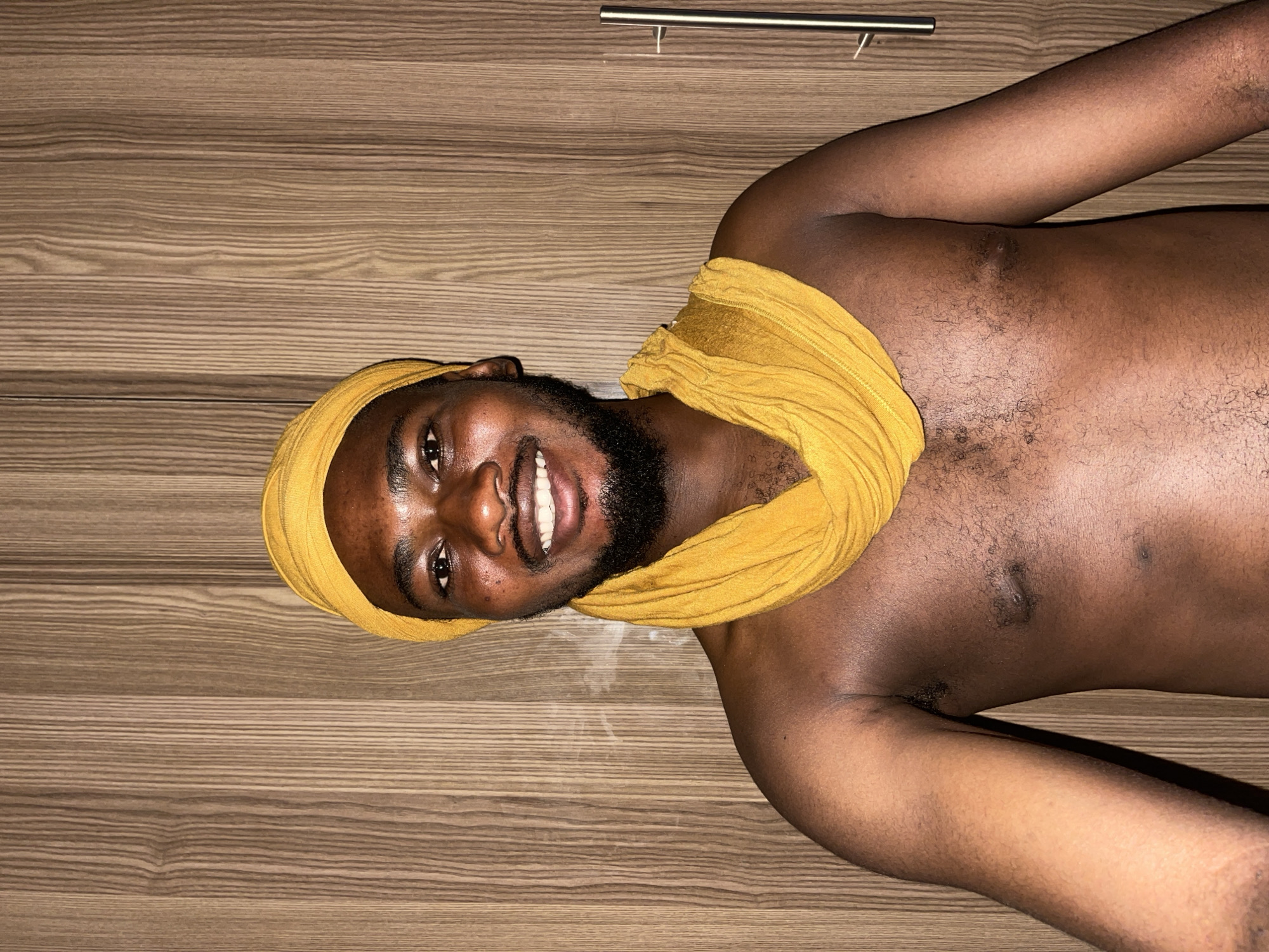 Man in yellow head wrap rests indoors in Muchiya