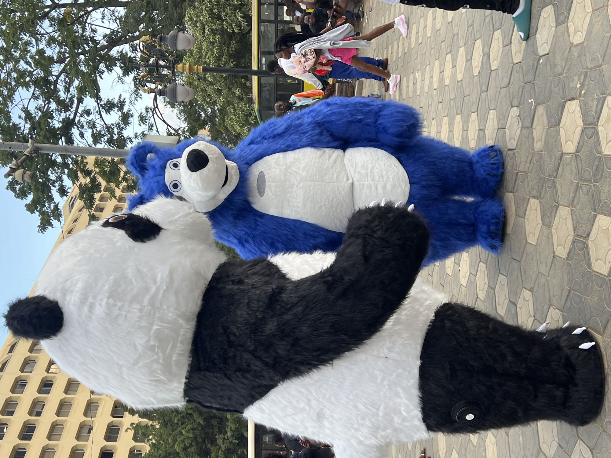 Street market bustles with vendors, food prep, mascots in Nairobi