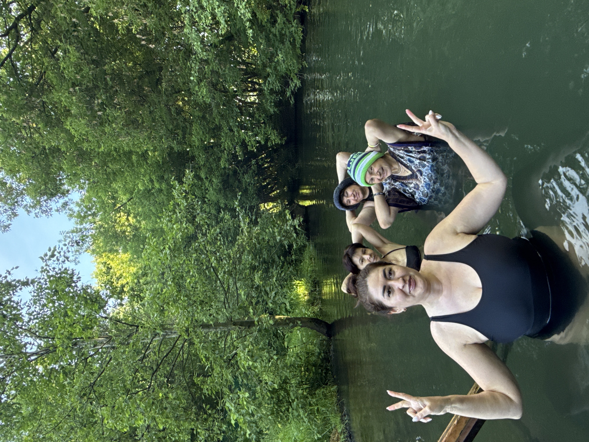 Group wades in green river near Kazan, one in a novelty hat