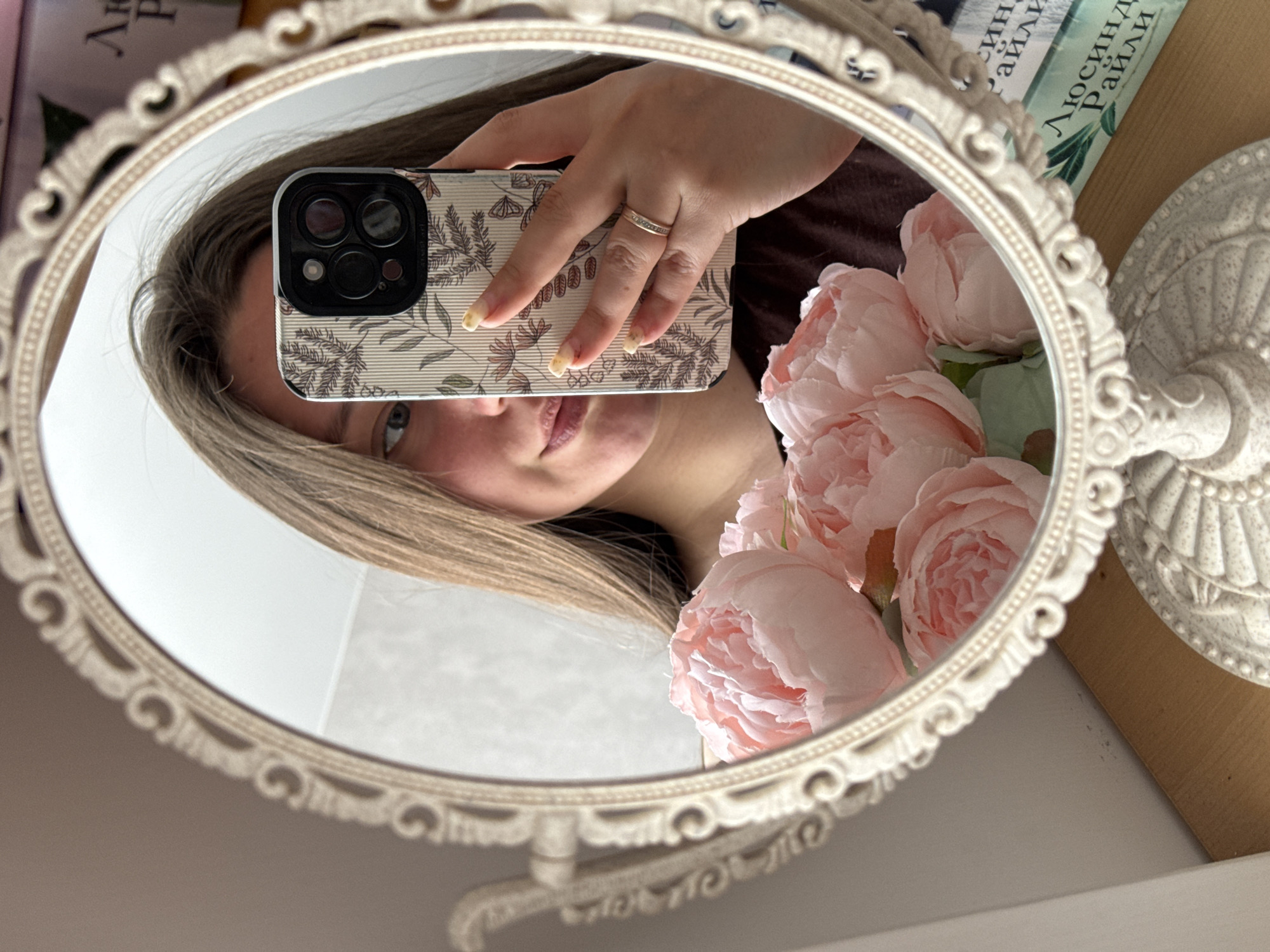 Woman takes mirror selfies with ornate oval mirror indoors