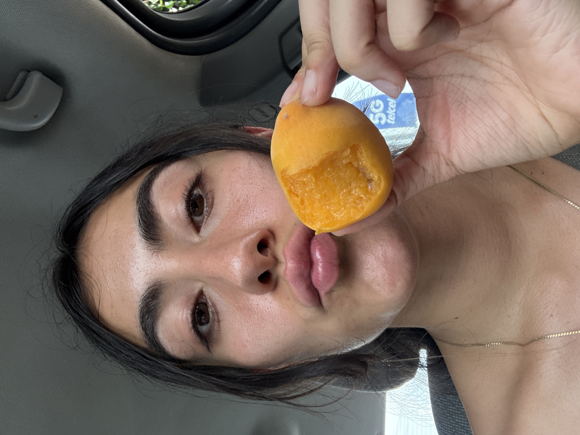 Woman eats apricot in car in Puebla, Mexico