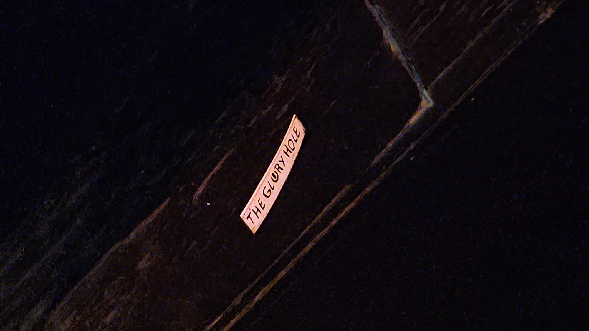 Wooden sign reading "The Glory Hole" photographed in Buenos Aires