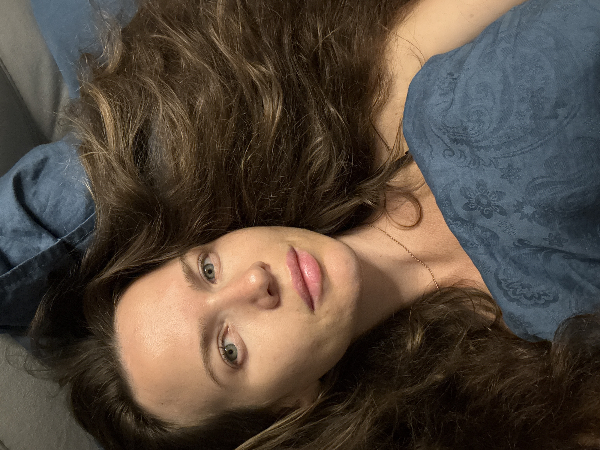 Relaxed moment in bed, blue bedding, direct gaze at camera