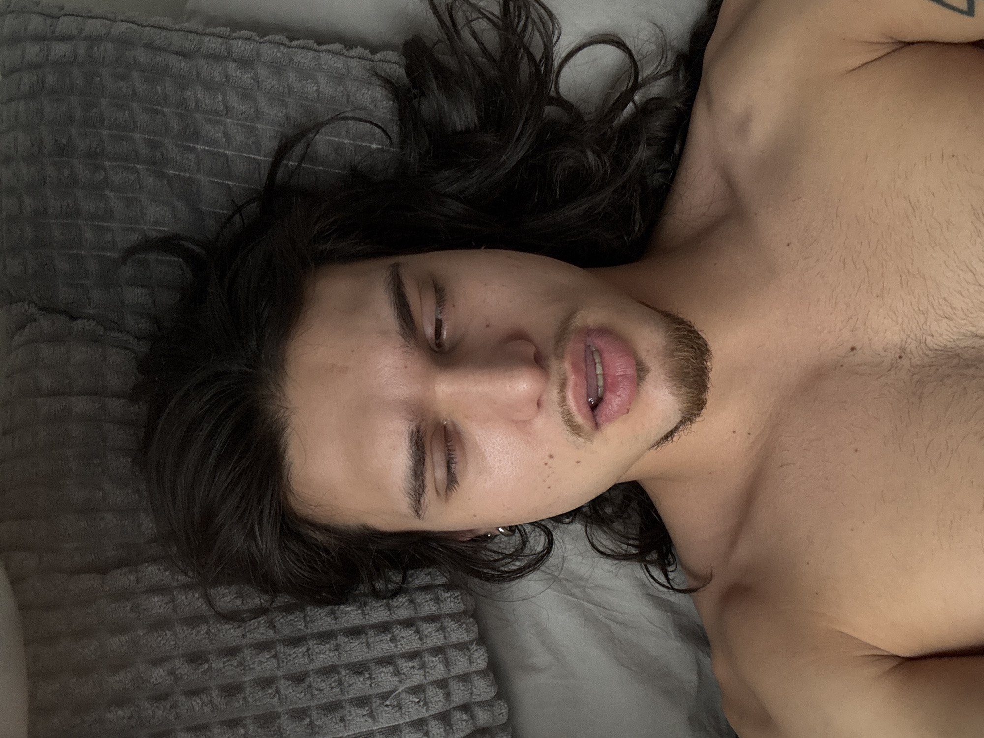Man with piercings rests in bed in Sofia