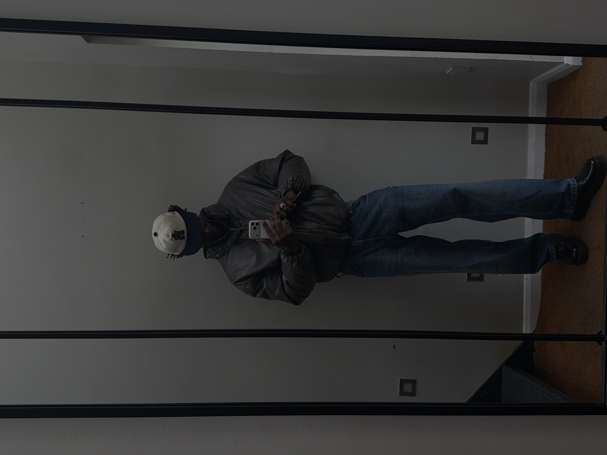 Person in layered winter clothing reflected in mirror, London