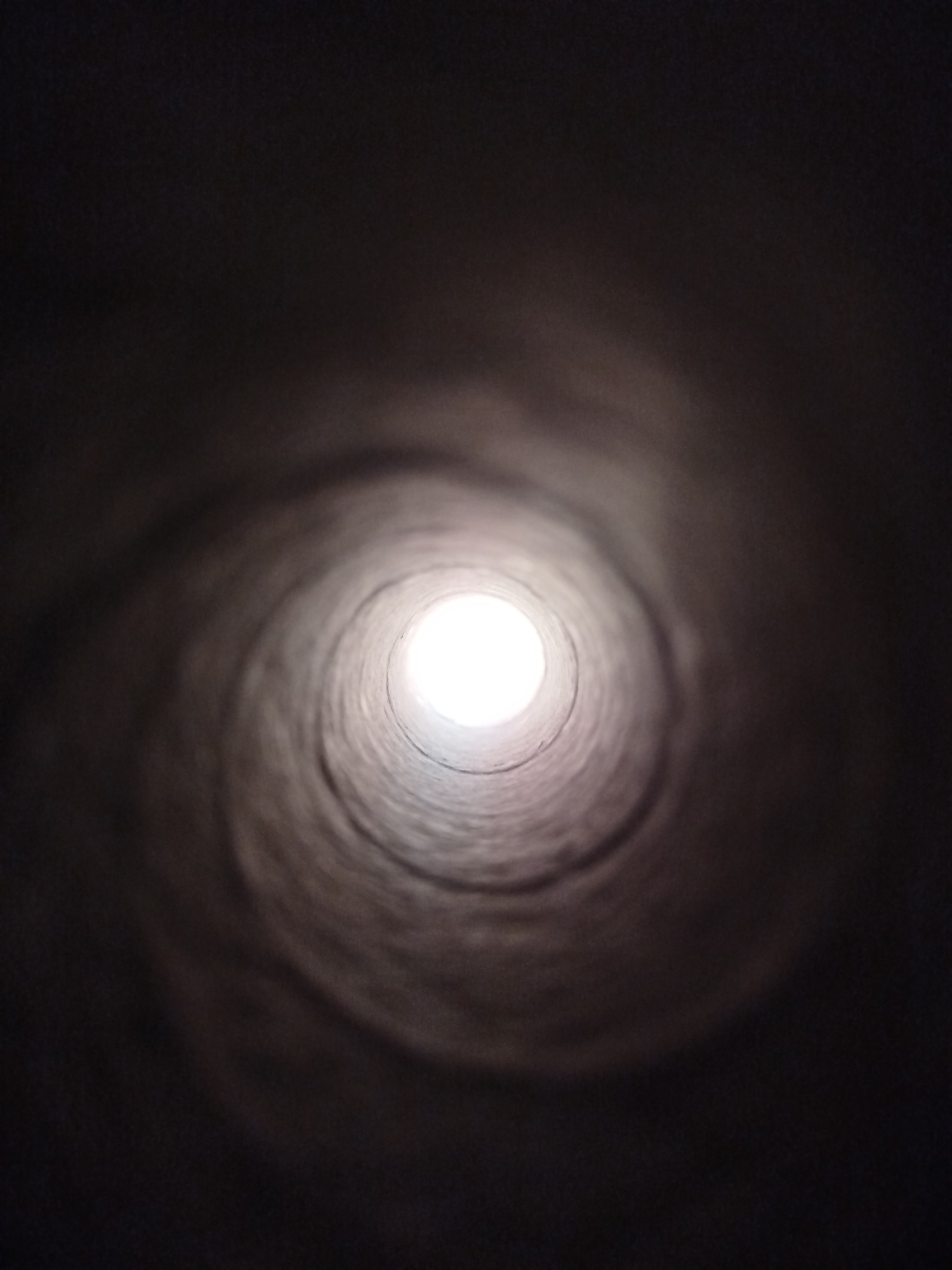 Inside a dark concrete tunnel, light at the end