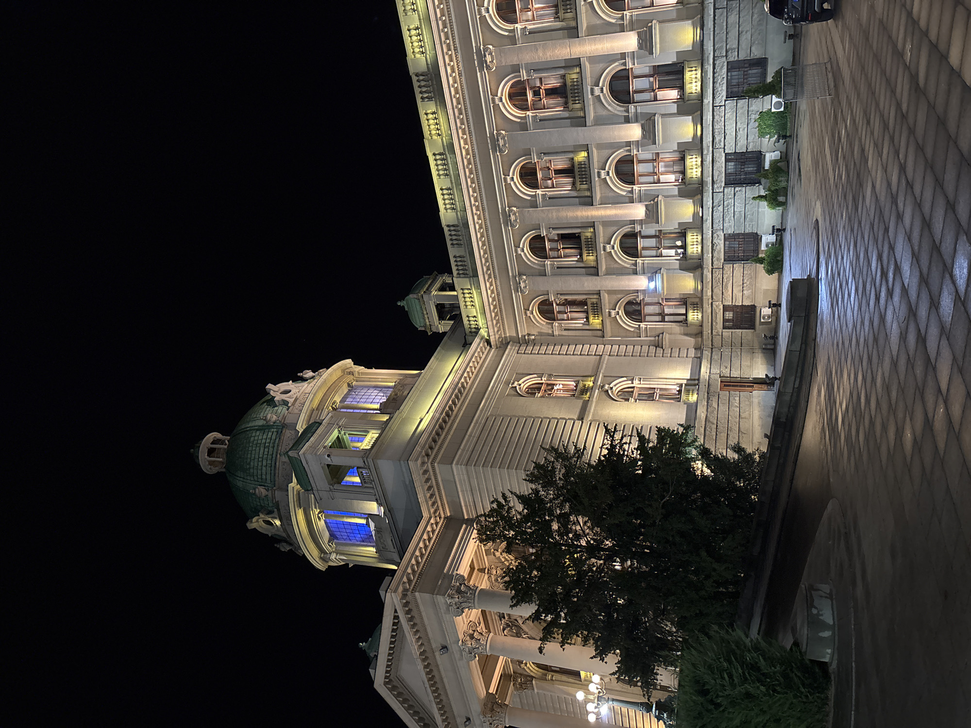 Night streets, lit monuments, and layered street art in a Balkan city