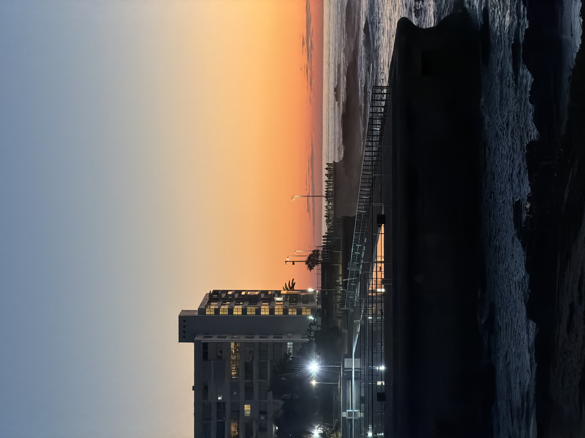 Sunset observed over Cape Town waterfront with illuminated streetlights