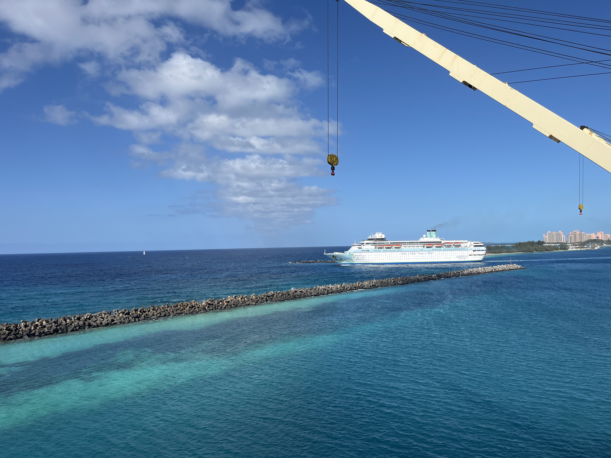 Cruise ship passes breakwater in turquoise waters