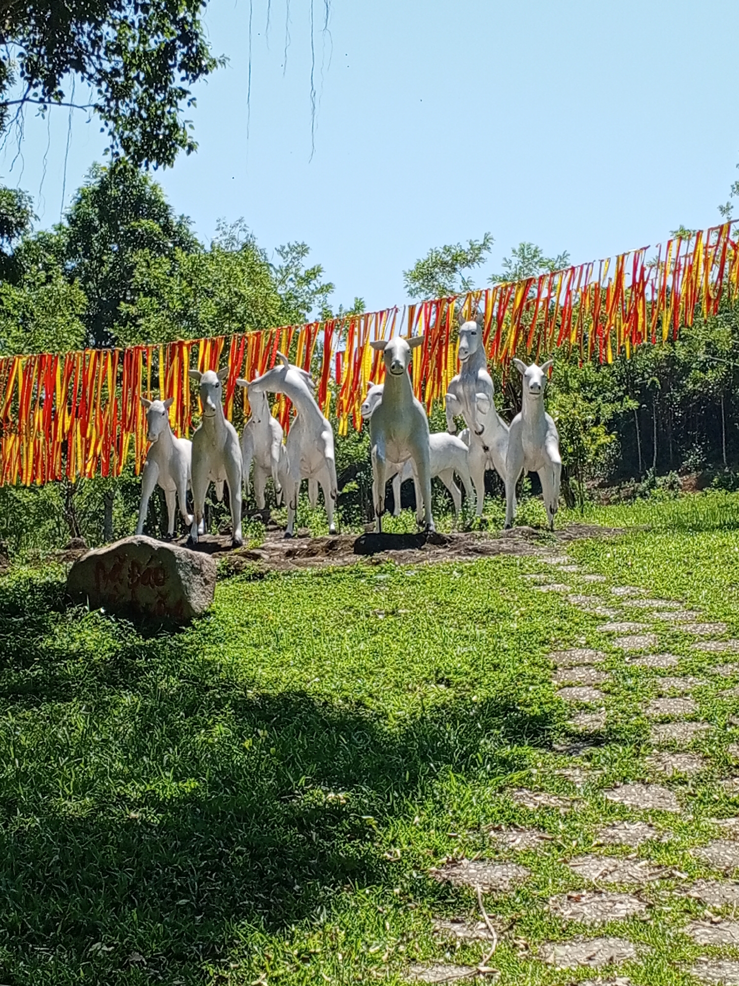 Horse statues and ribbon-wrapped sacred tree at Khanh Vinh shrine