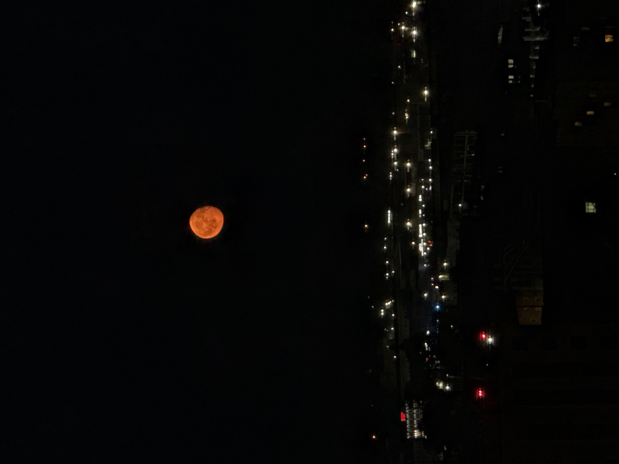 Orange full moon rises over Perm city at night