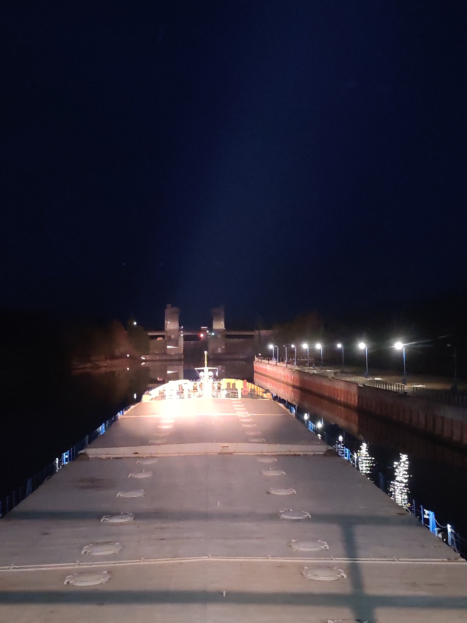 Cargo ship navigates illuminated waterways near Vytegra at night