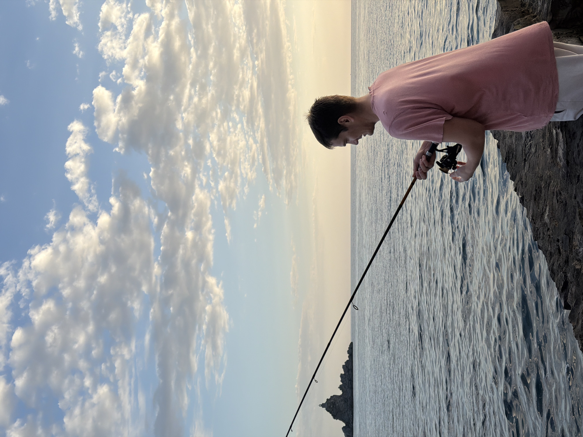 Man fishes from rocky shore in Petrovac, Montenegro