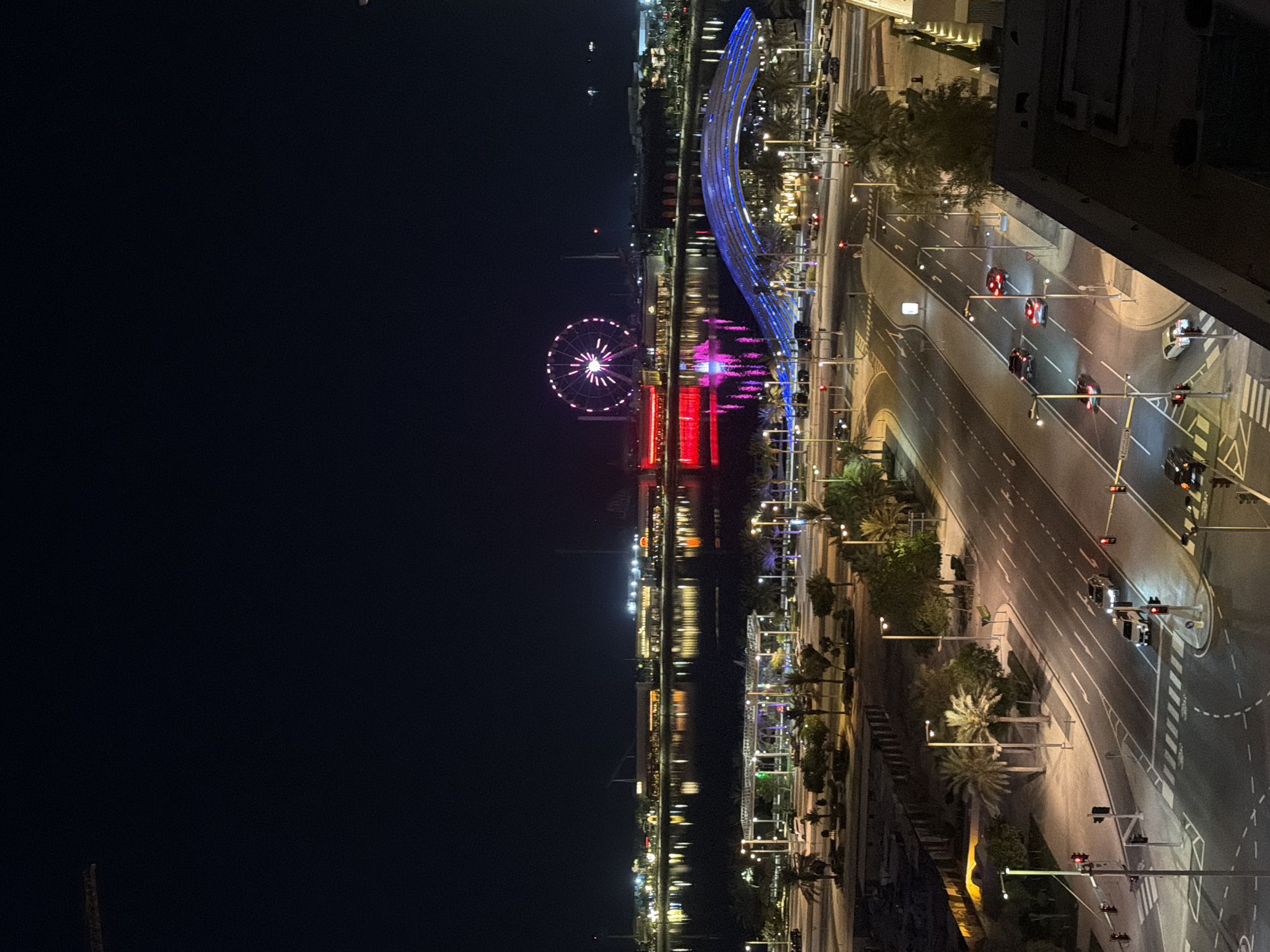 Pink-lit Ferris wheel observed from high vantage point in Lusail