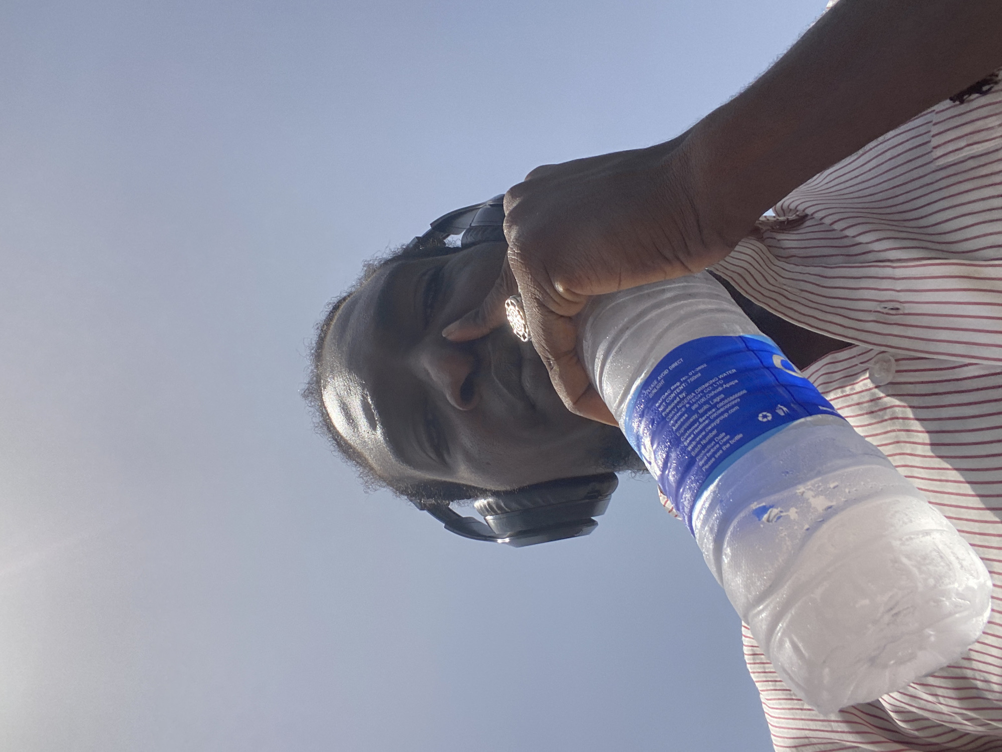 Man with headphones holds water bottle on cracked earth
