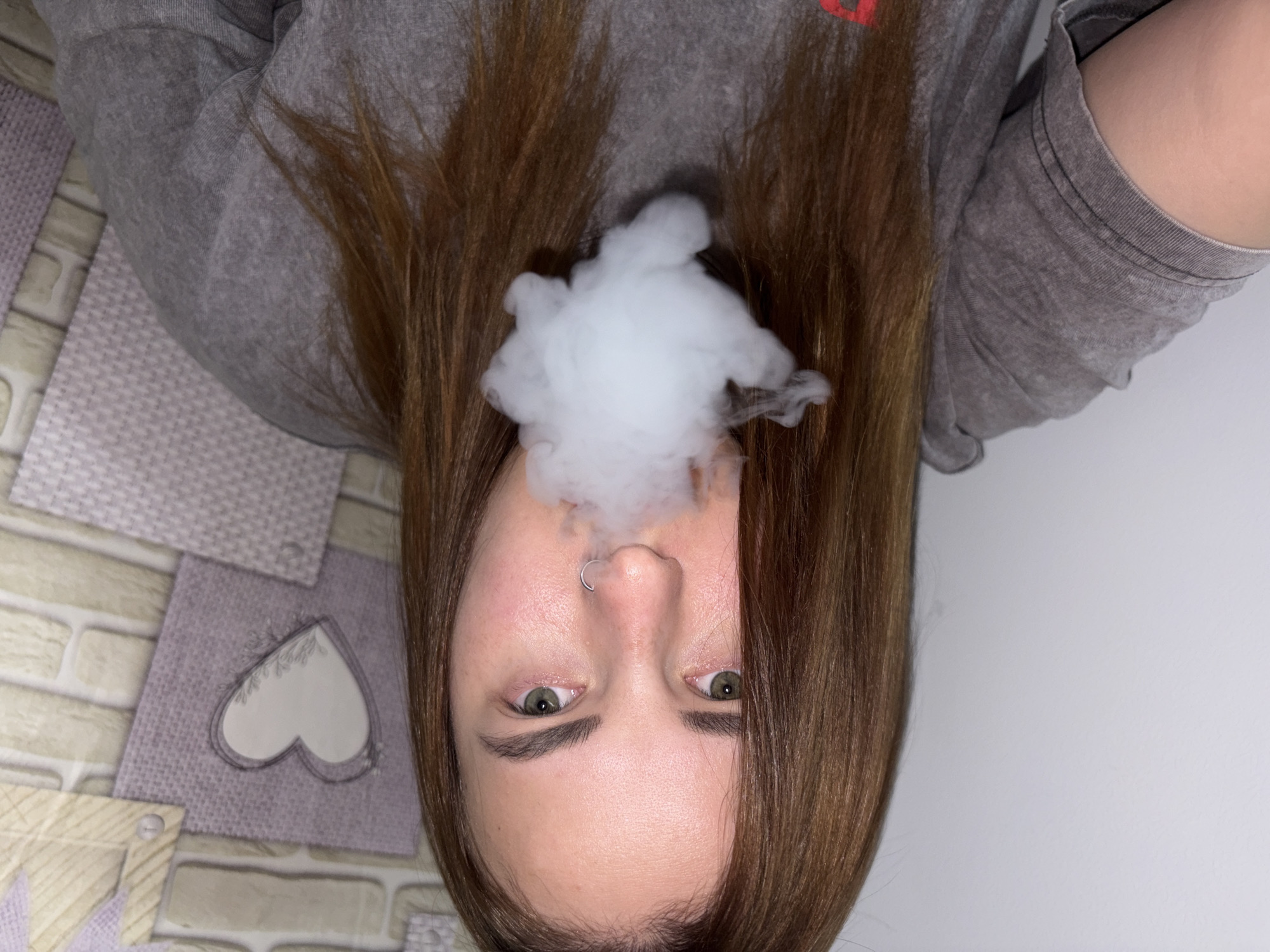 Upside-down portrait captured with nose piercing, smoke visible